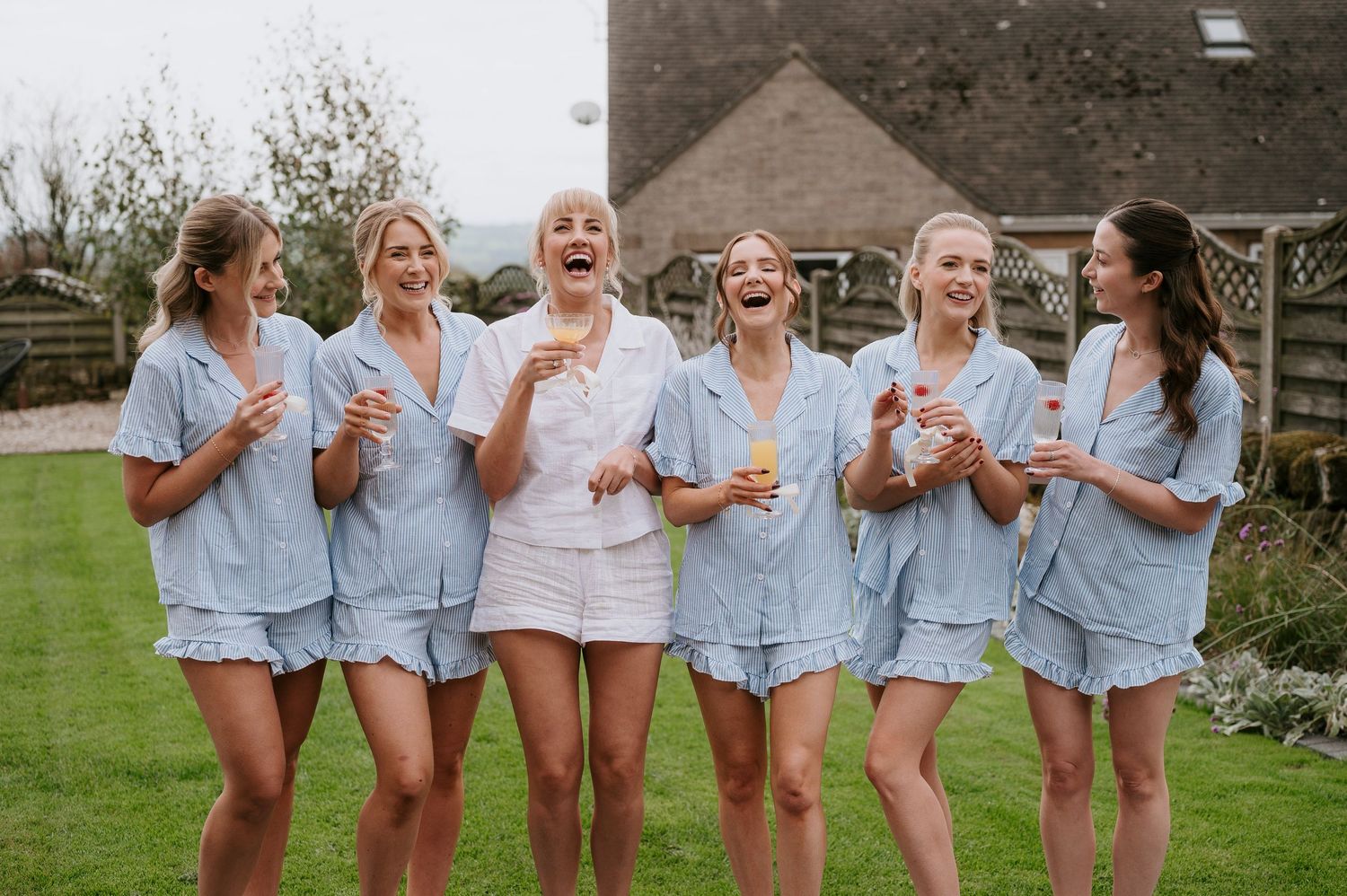 Group of friends in coordinated light blue outfits laughing and having fun together outdoors.