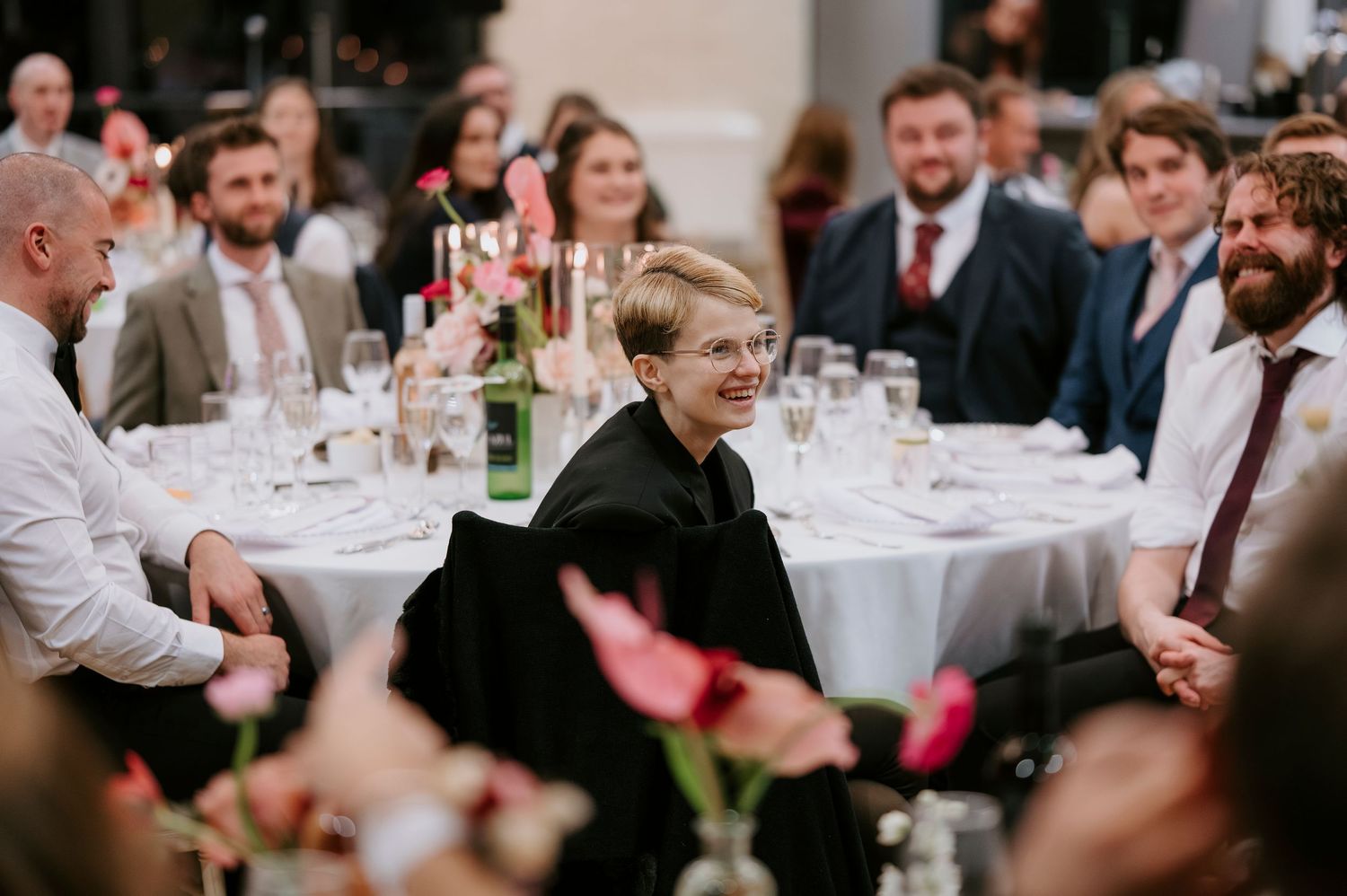 Wedding guests seated at round tables during an elegant reception dinner with white tablecloths and wine glasses.