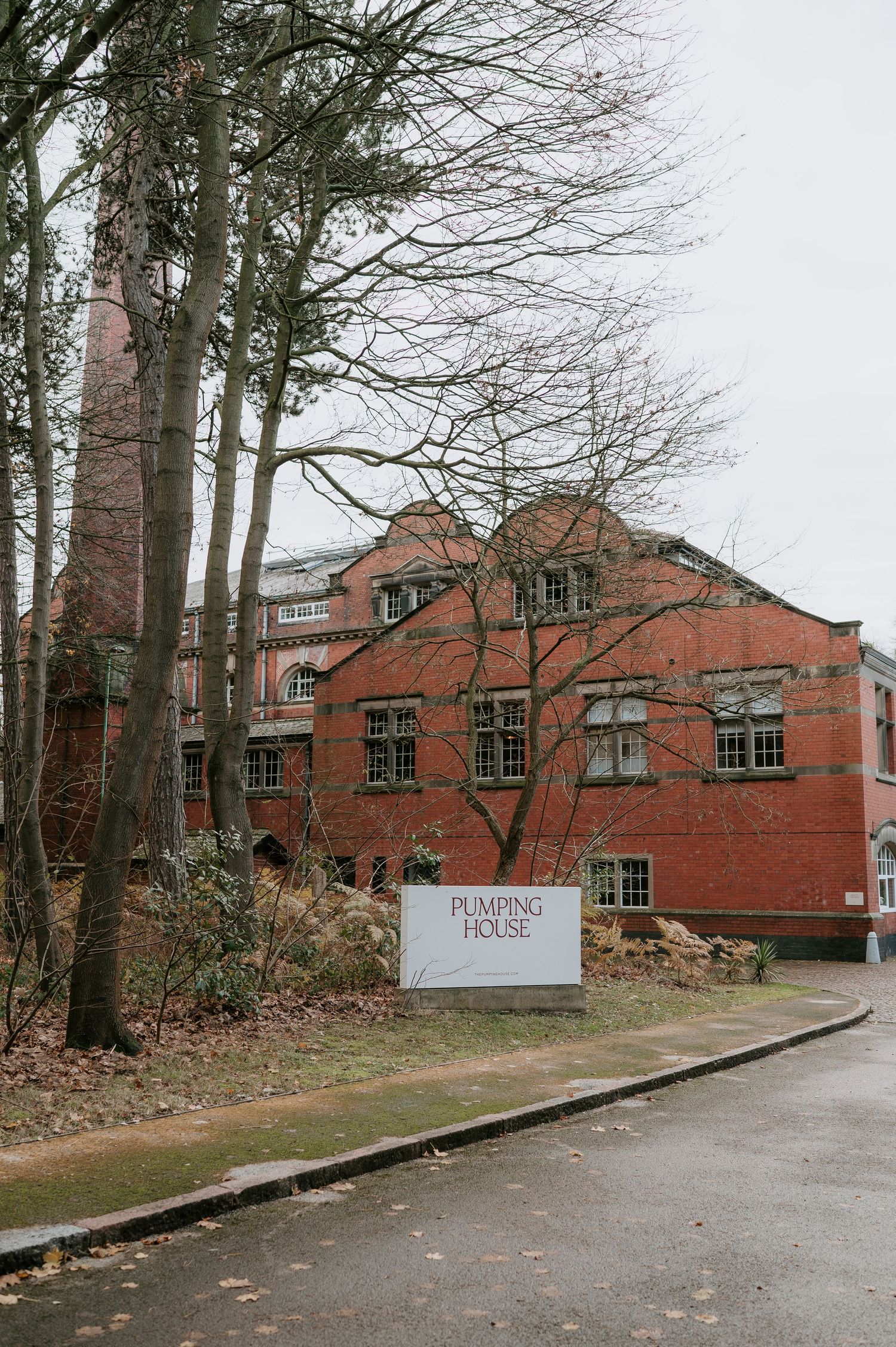 Exterior view of a historic red brick building with multiple windows and bare trees in winter.
