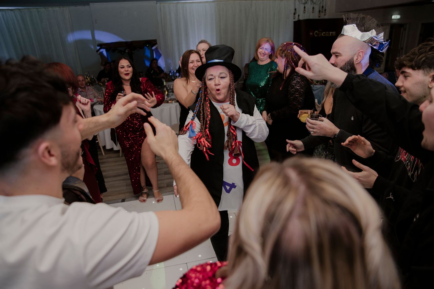 Guests dance and celebrate on a dimly lit dance floor during a lively wedding reception.
