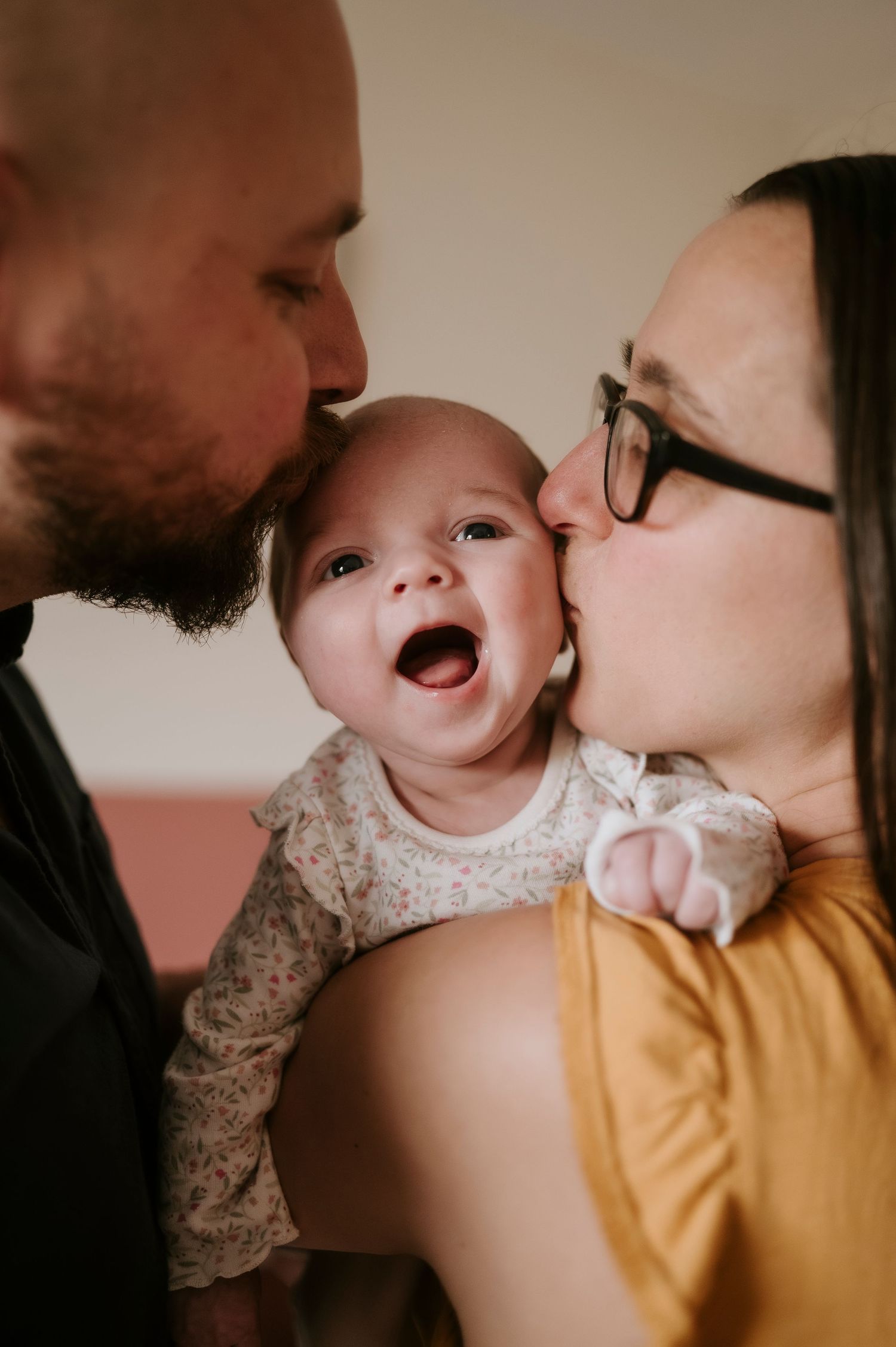 A series of tender moments showing a baby being kissed while wearing a white lace dress and yellow clothing.