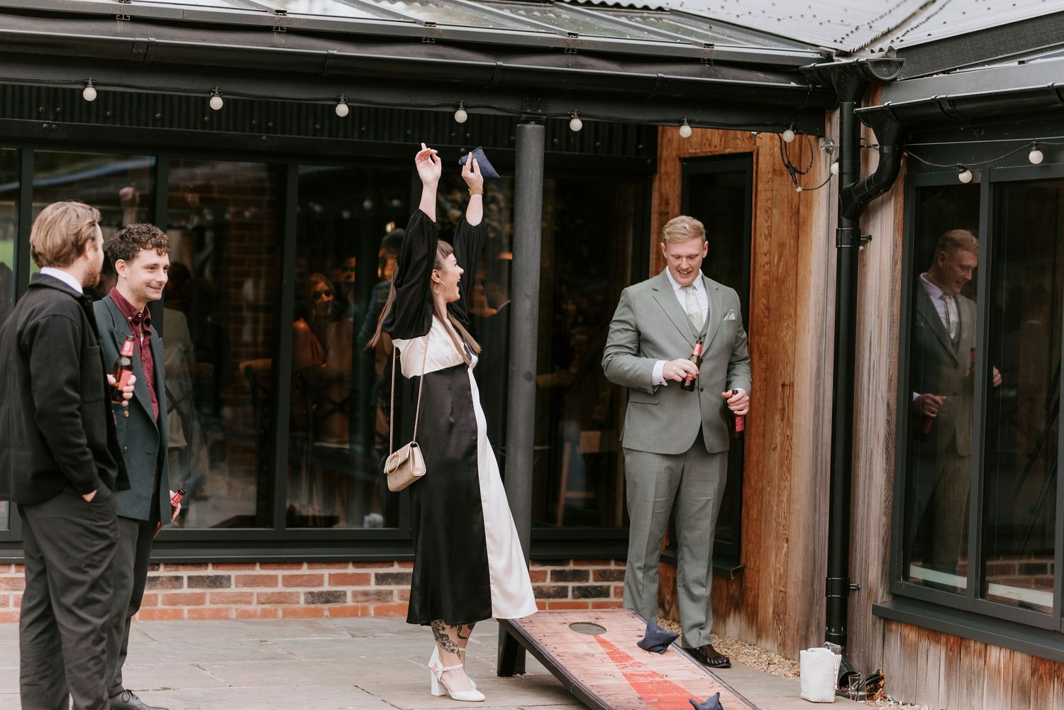 A series of black and white wedding photos showing candid moments between guests and wedding party outside a venue.