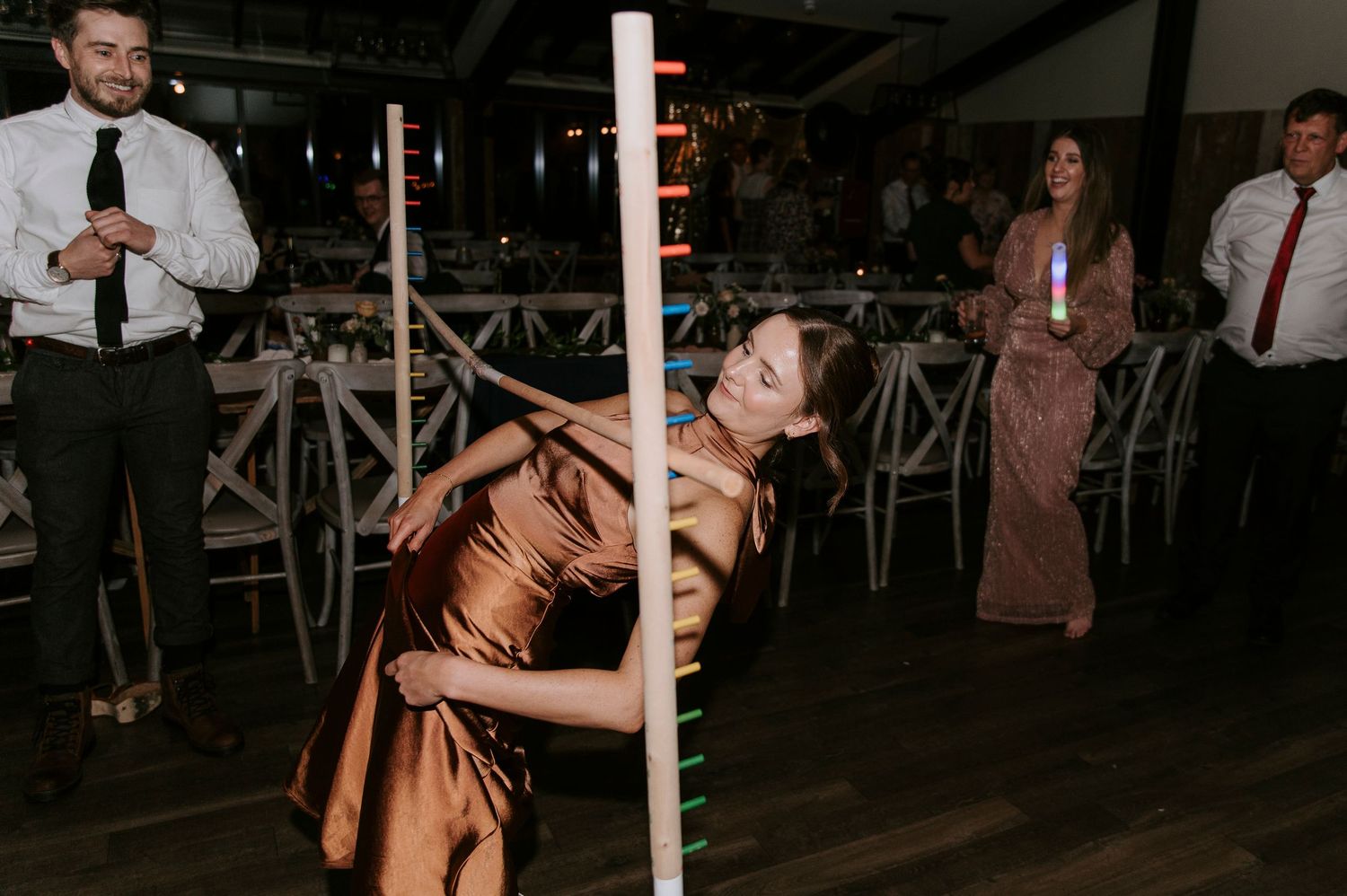 People dancing and celebrating at a dimly lit wedding reception venue.