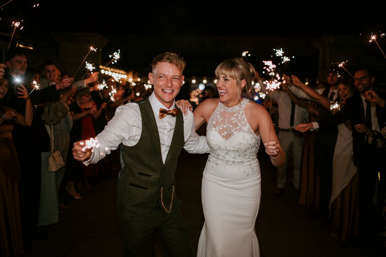 Wedding guests celebrate with sparklers during a nighttime send-off celebration.