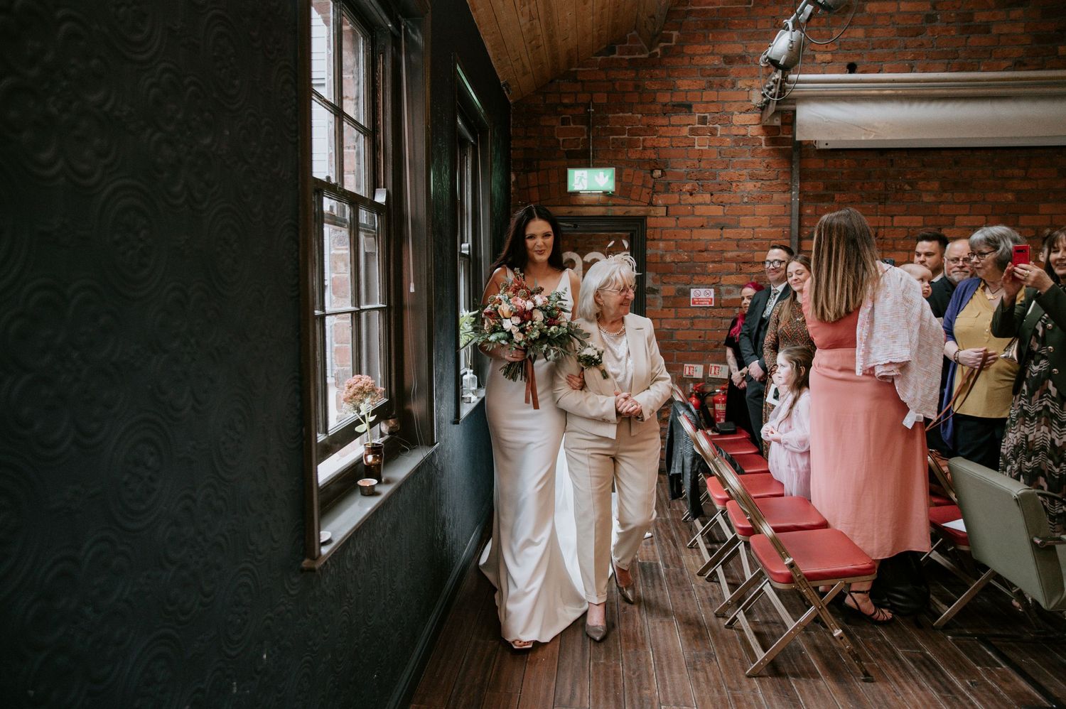 Wedding party walking through a vintage brick hallway decorated with natural light.