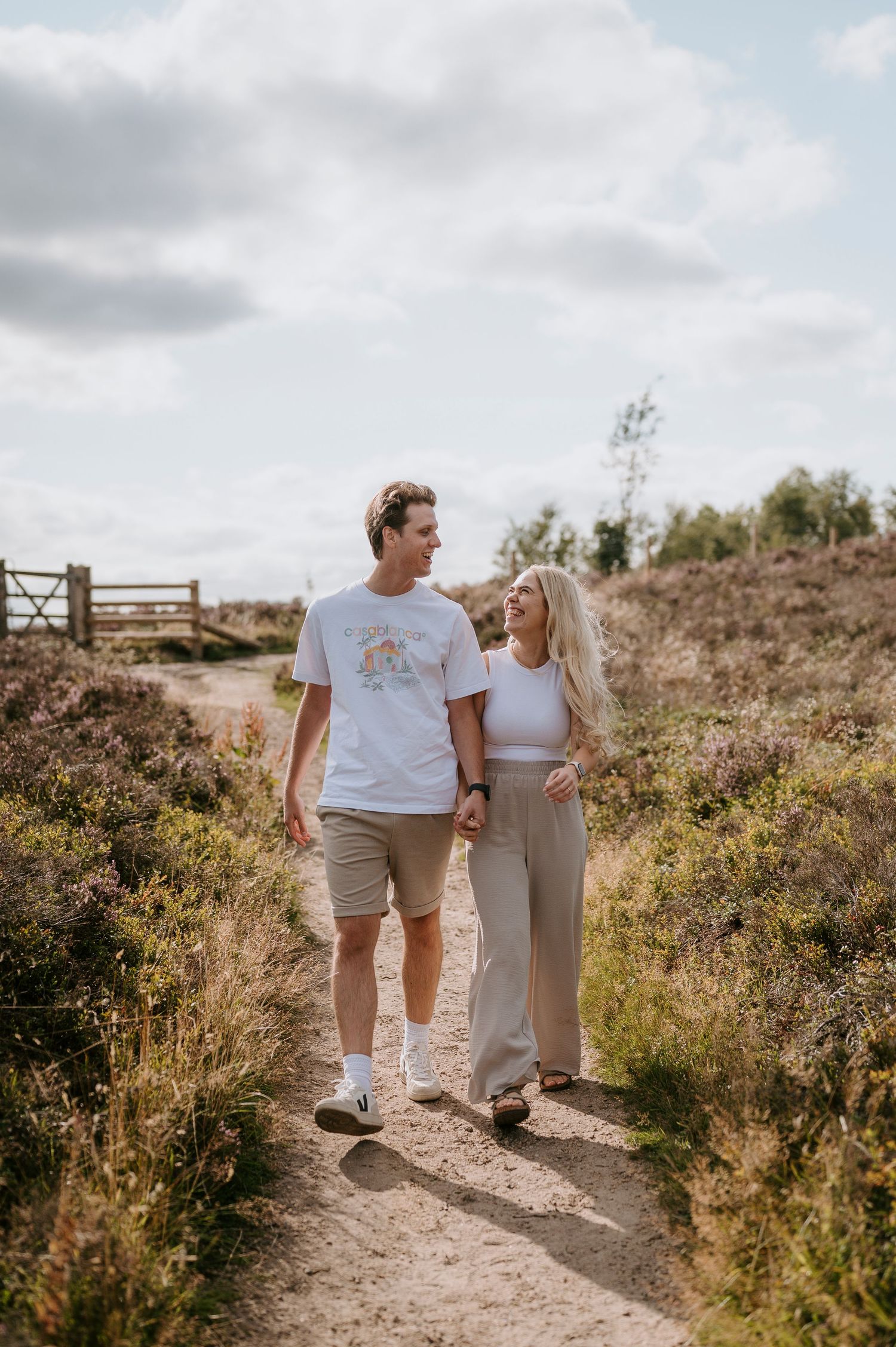 A couple walking together on a scenic nature trail through wild brush on a cloudy summer day.