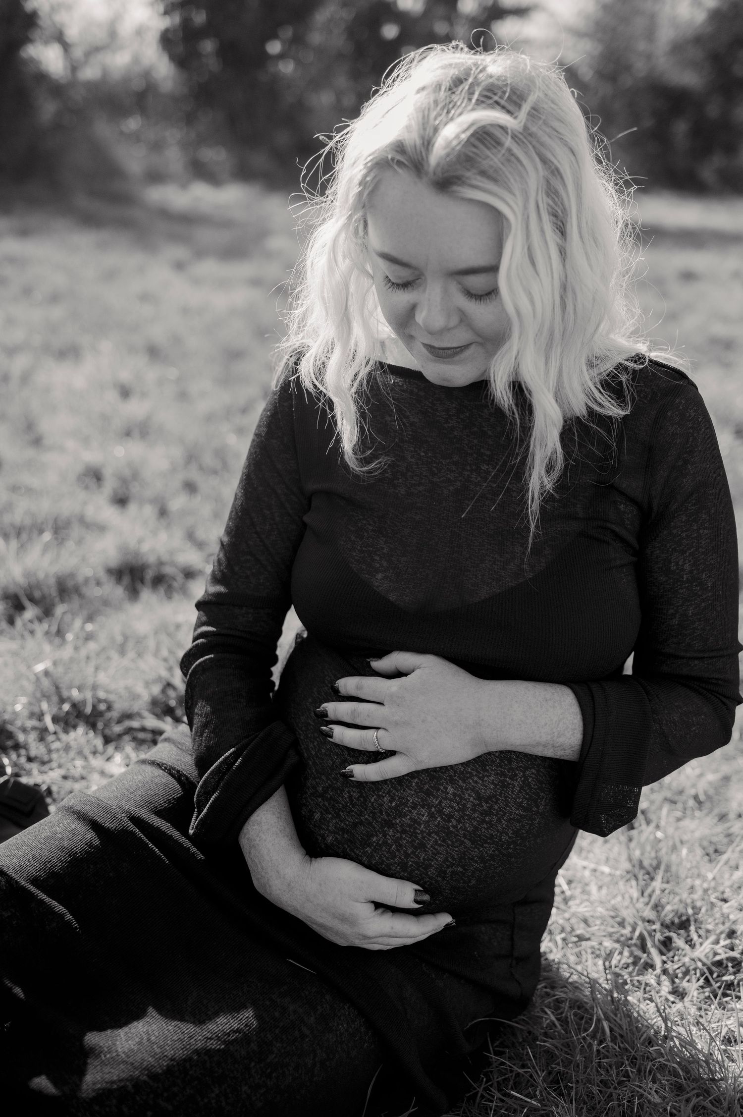 Black and white maternity photography series capturing tender moments in natural sunlight.