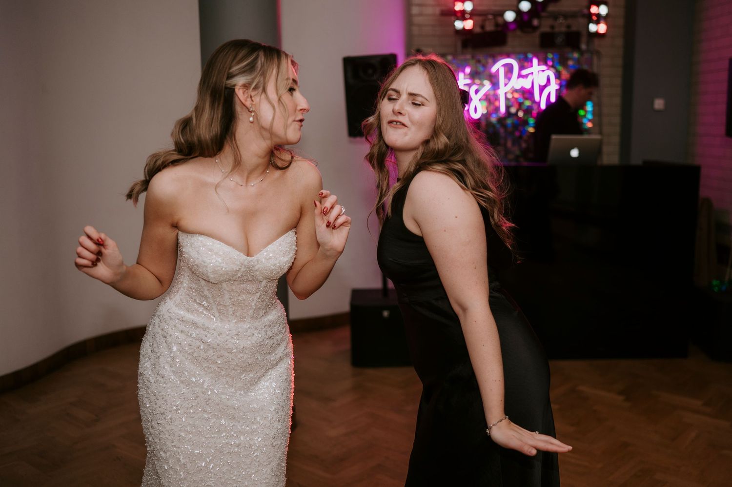 Wedding reception dance floor with colorful lighting and guests dancing.