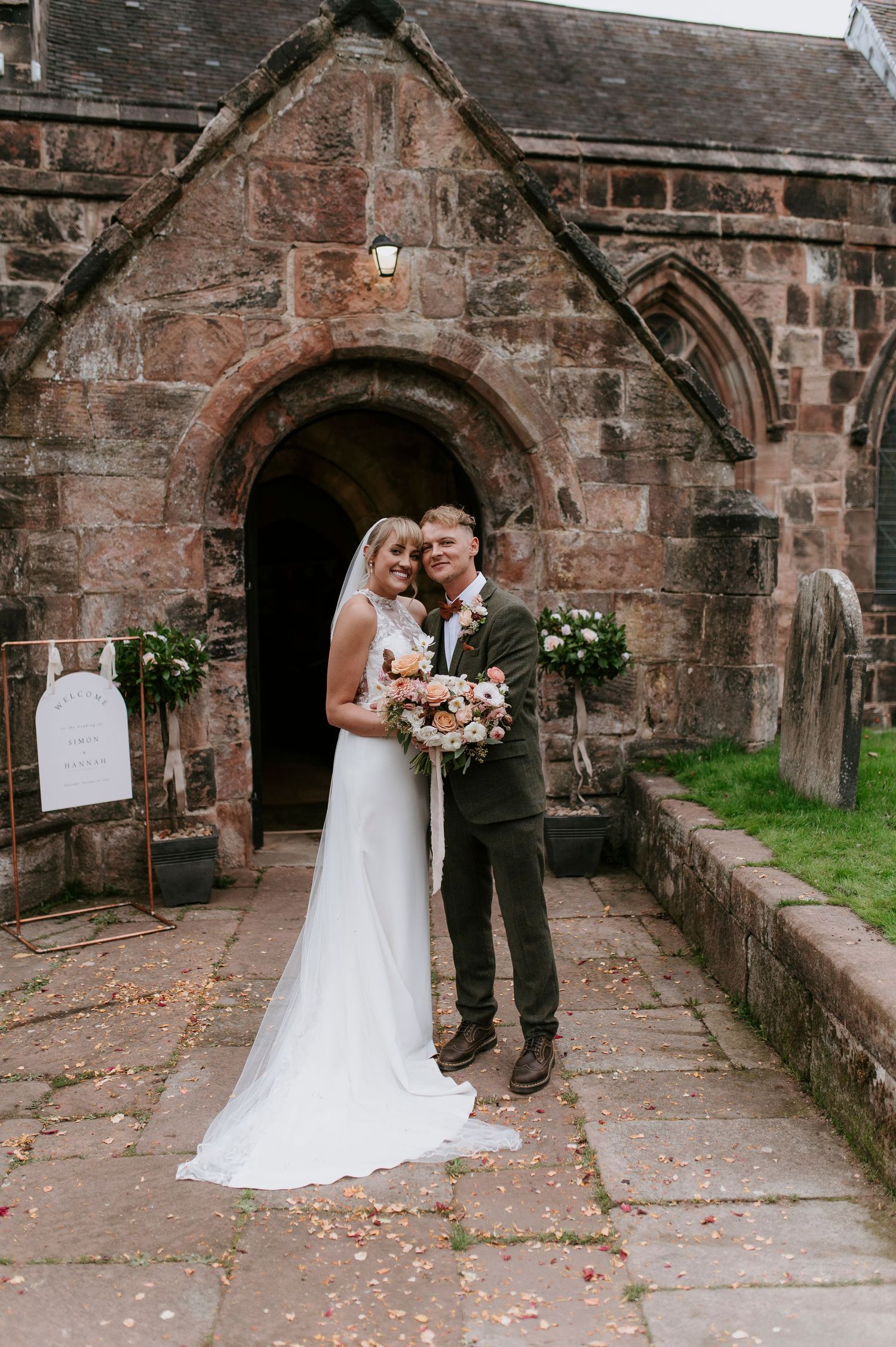 A wedding couple shares intimate moments in a rustic stone archway corridor adorned with scattered rose petals.