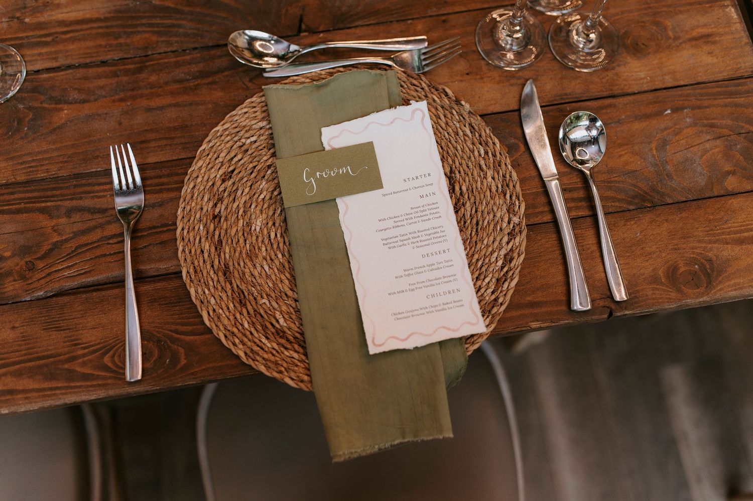 Rustic wooden table setting with woven placemats, wine glasses, and menu cards in an elegant restaurant atmosphere.