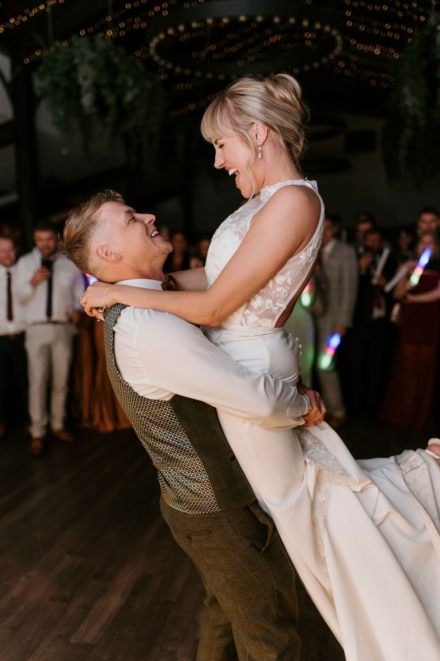 A couple shares a romantic dance at their wedding reception as the groom dips the bride in a flowing white gown.