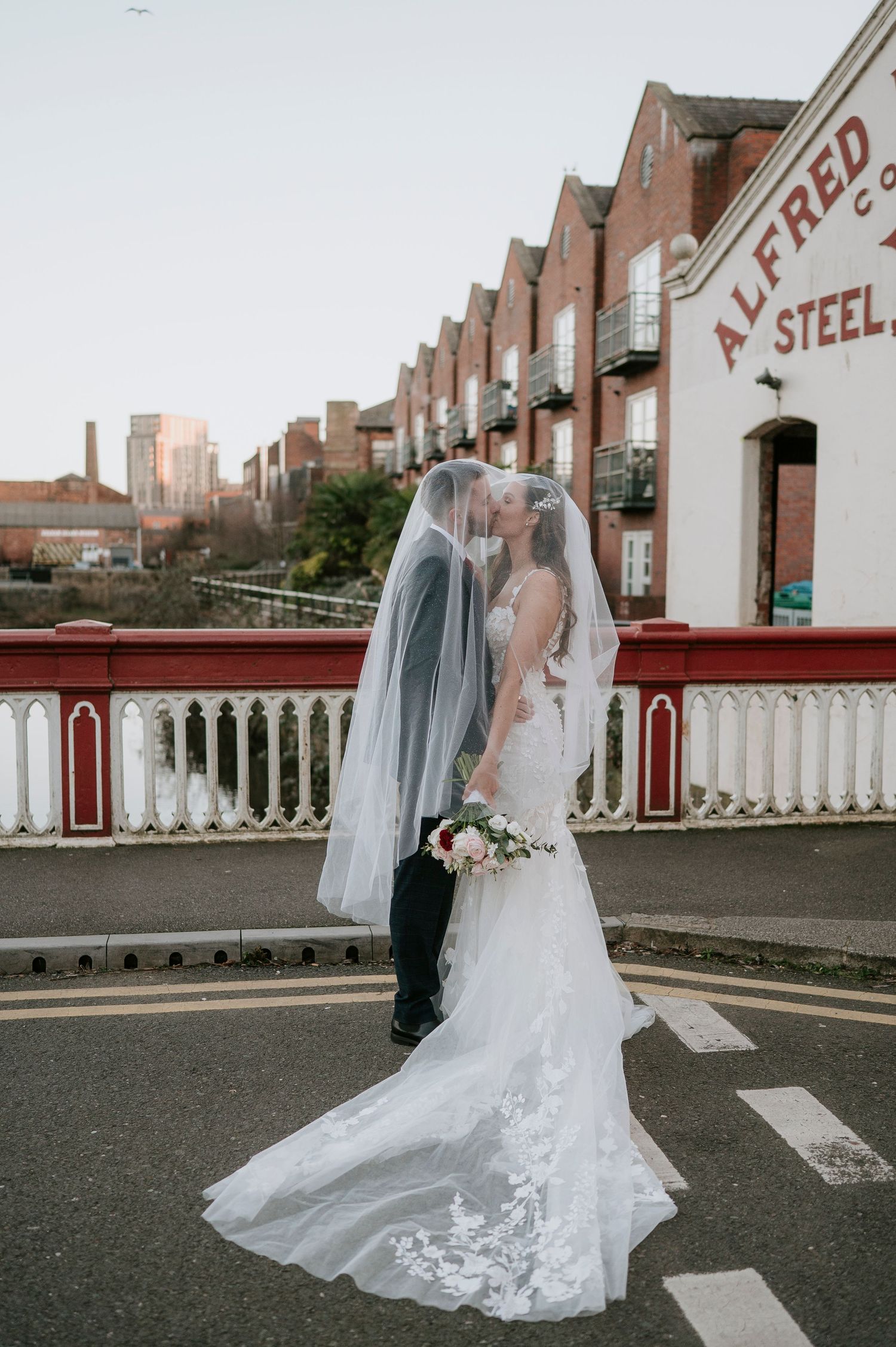 Elegant wedding dress with flowing lace veil photographed from different angles on an urban rooftop setting.