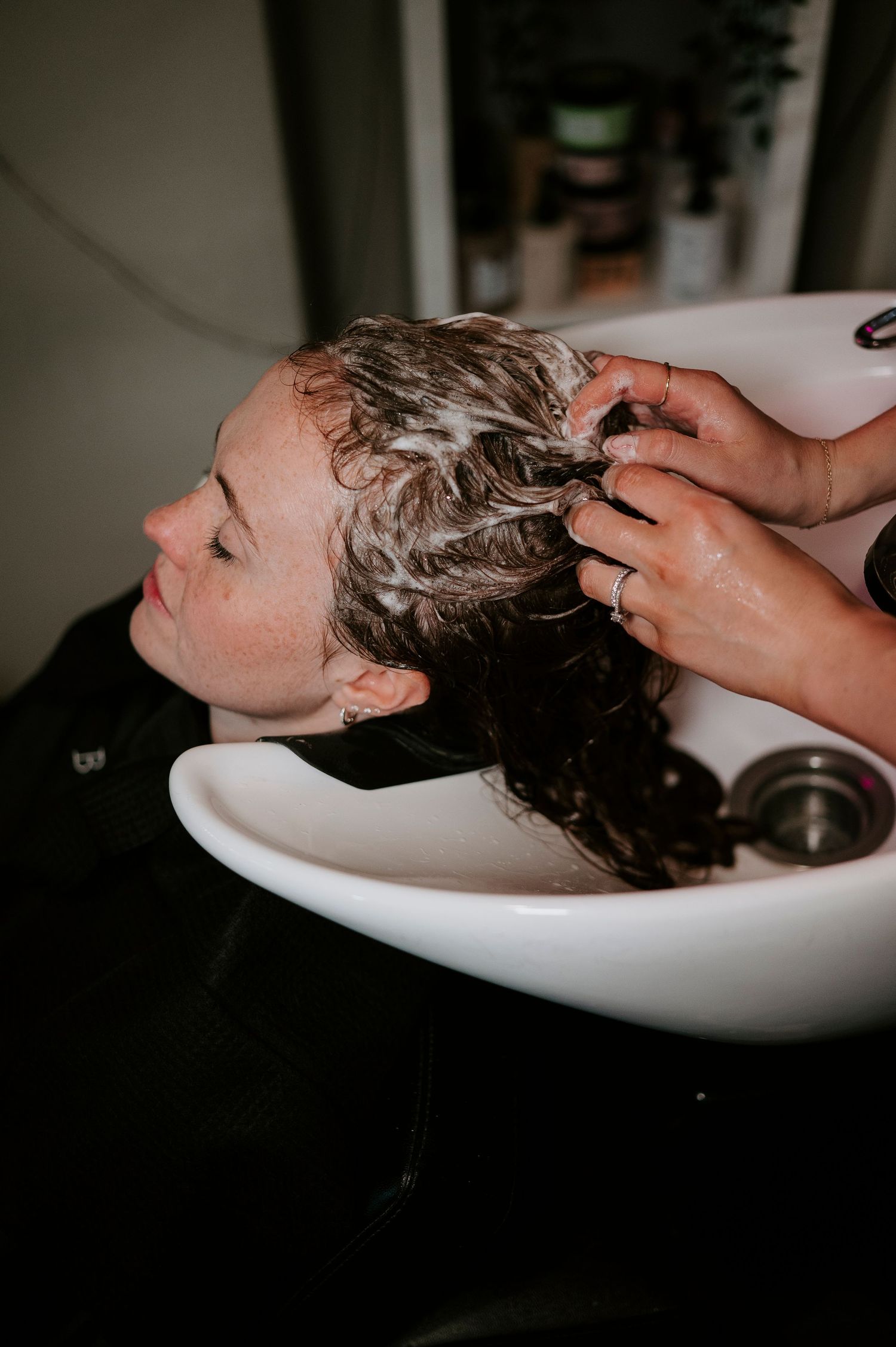 Hair washing and shampooing service being performed at a salon sink with lathered hair.