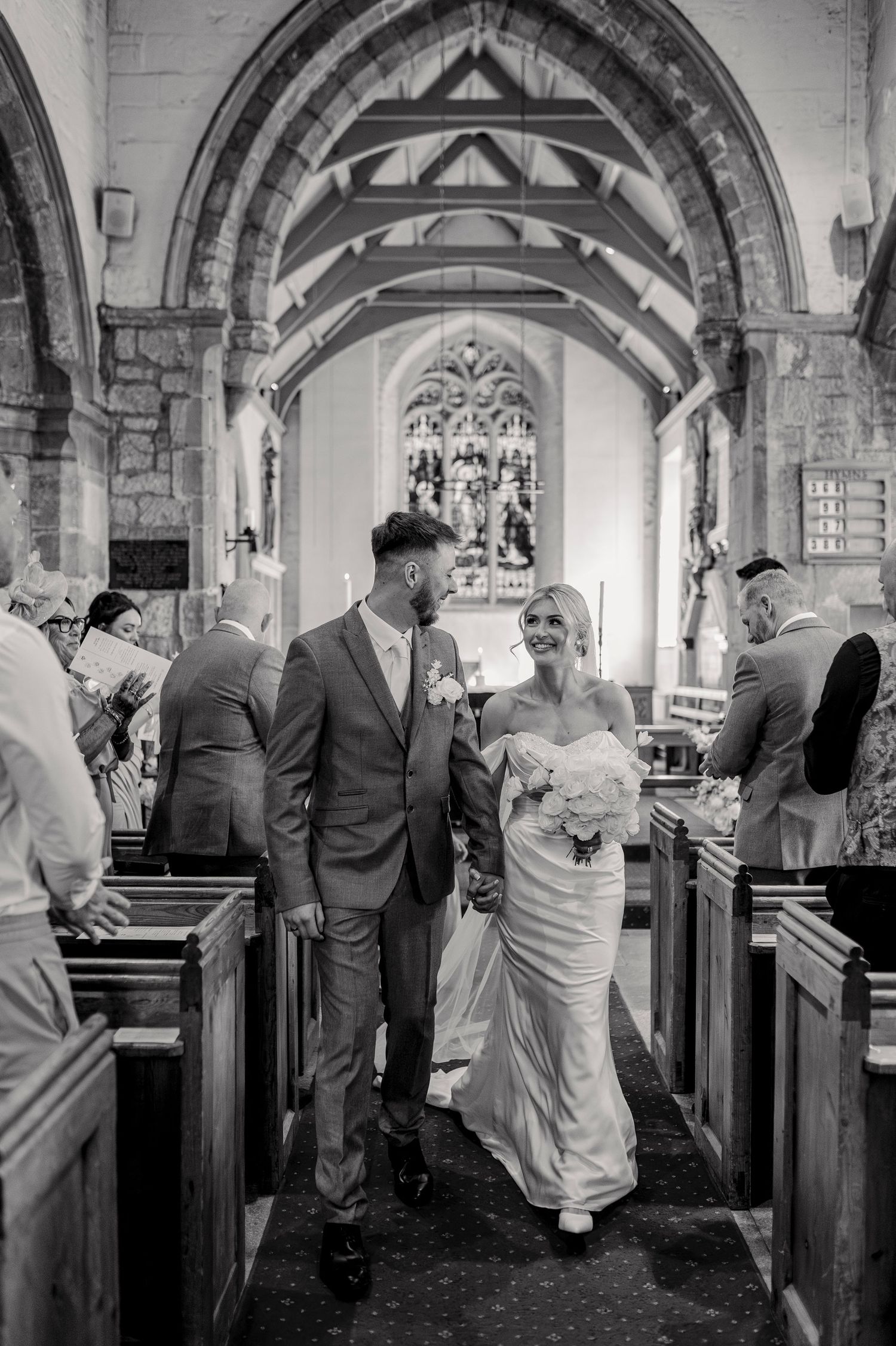 Black and white photo sequence showing a wedding couple walking through a historic church with stone arches and pews.