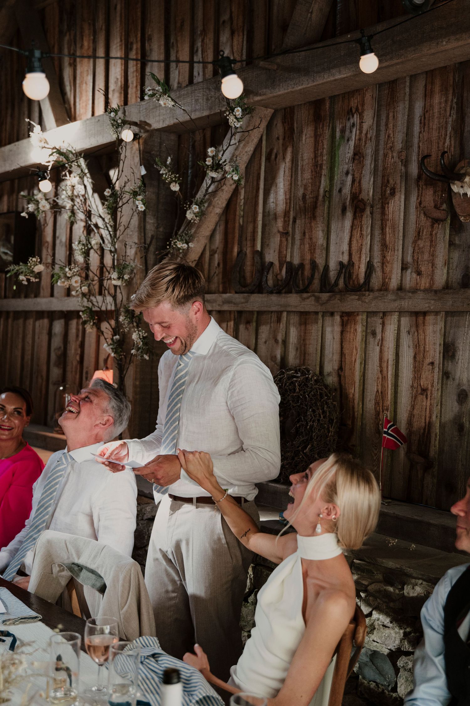 Wedding reception celebration in a rustic barn venue with hanging lights and decorations.