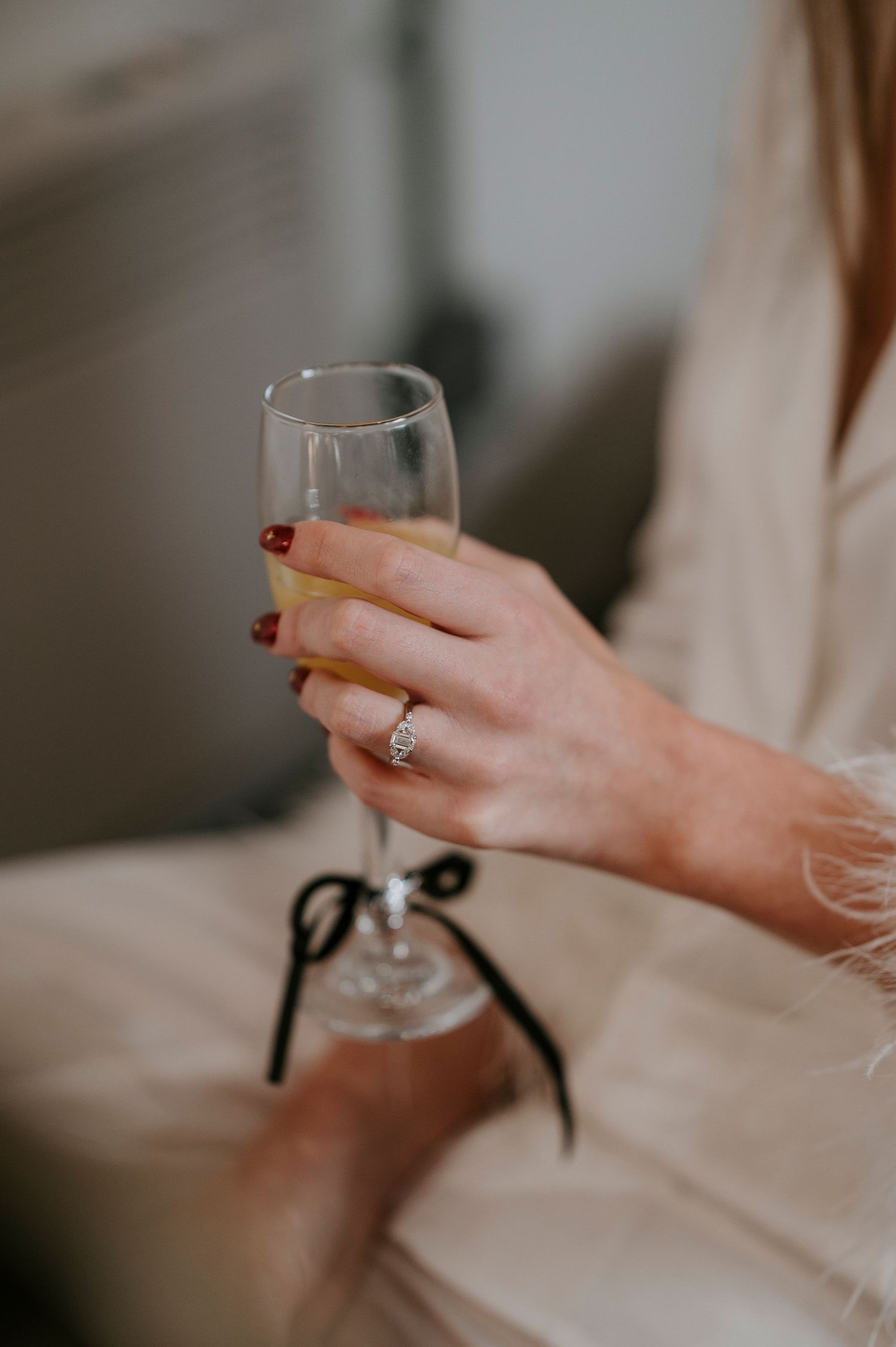 Hand holding a delicate wine glass against a soft, blurred background.