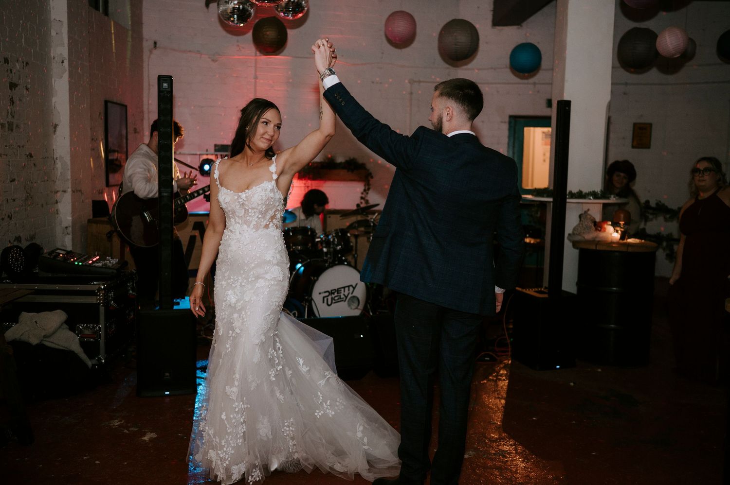 Bride and groom share first dance at wedding reception with live band performing in background.