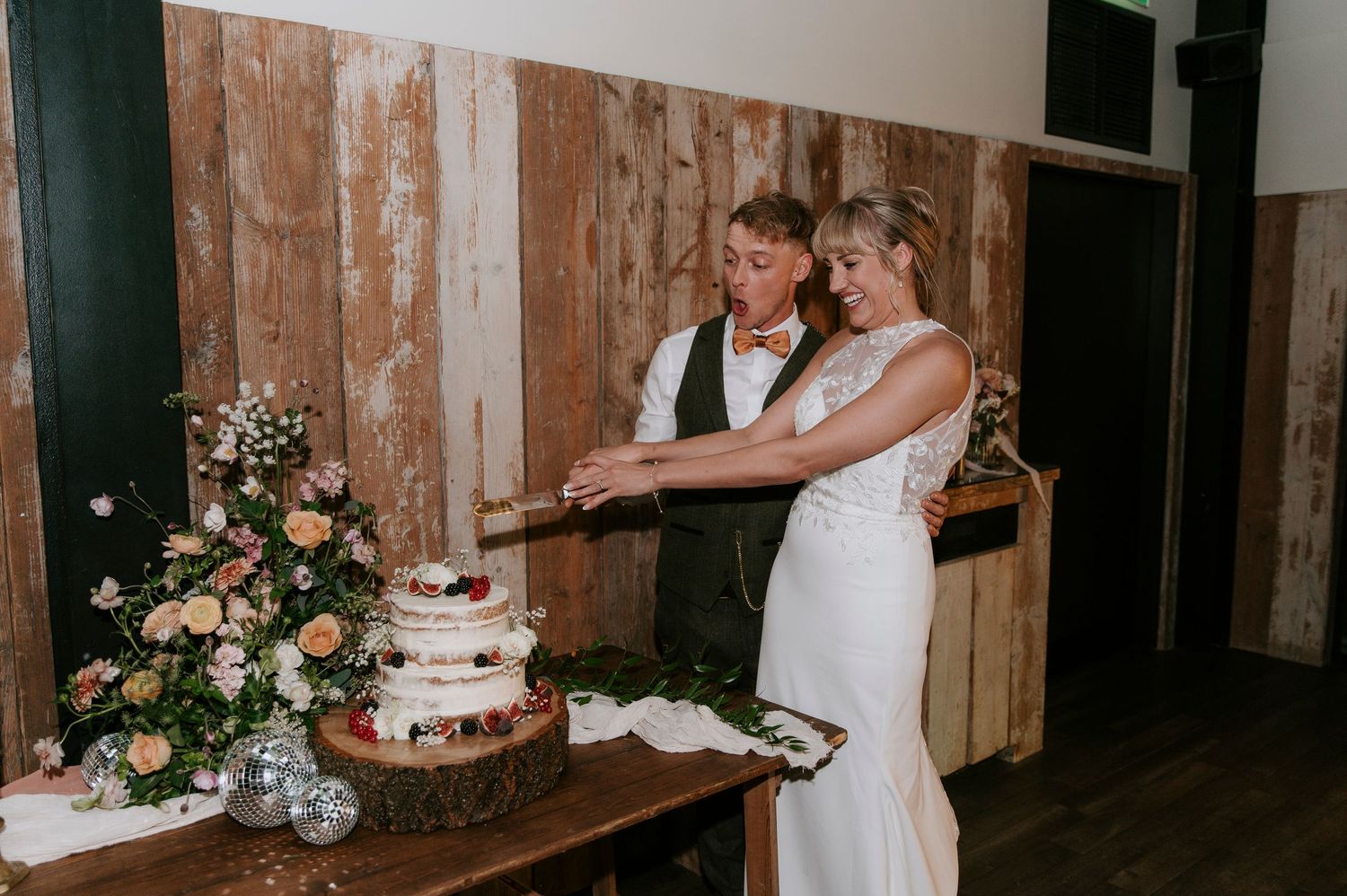 A rustic wooden wall serves as a backdrop for a wedding ceremony setup with floral arrangements and decor.