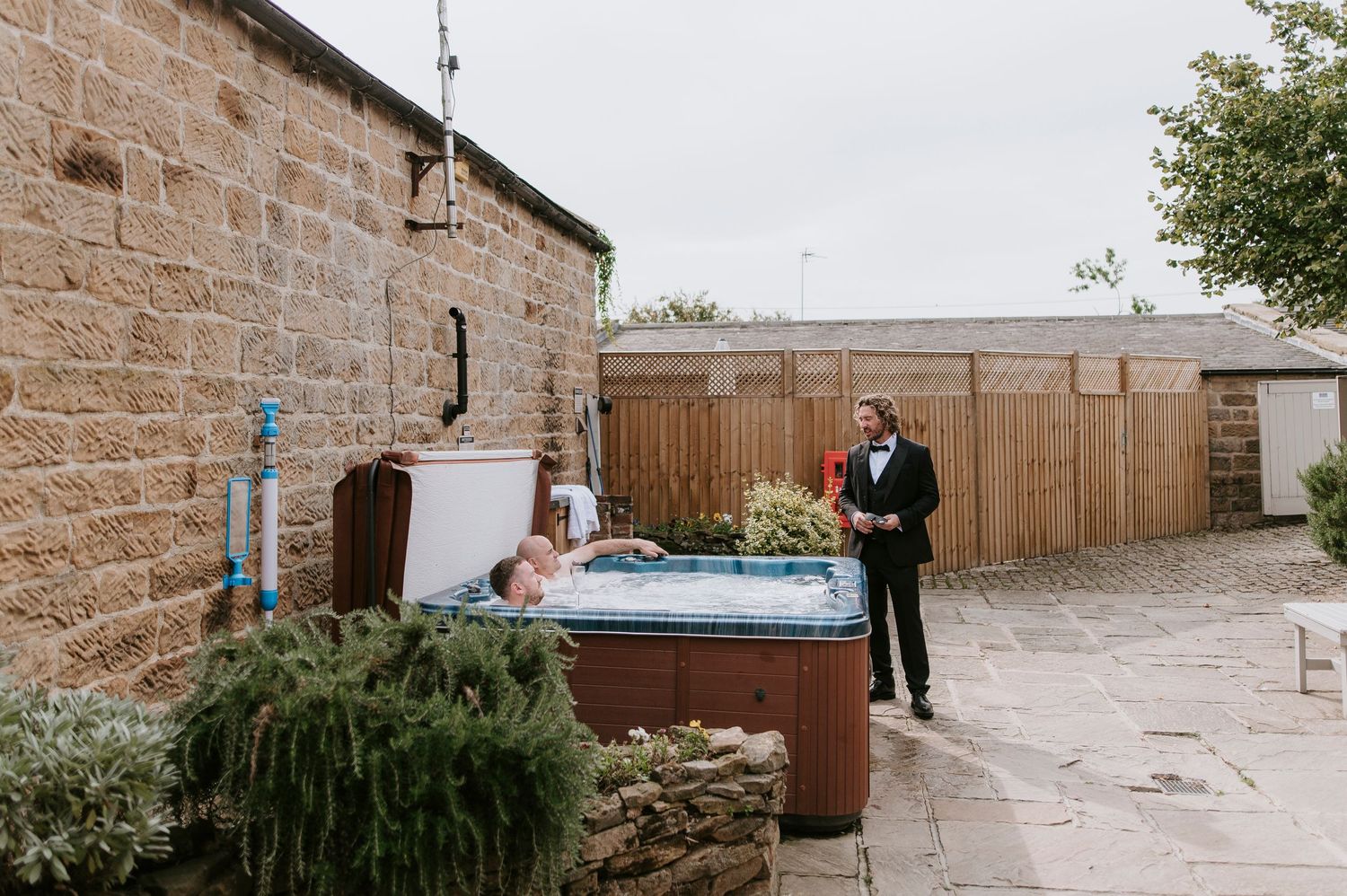 A sequence of wedding photos taken at a rustic stone venue with a wooden fence and hot tub in the background.