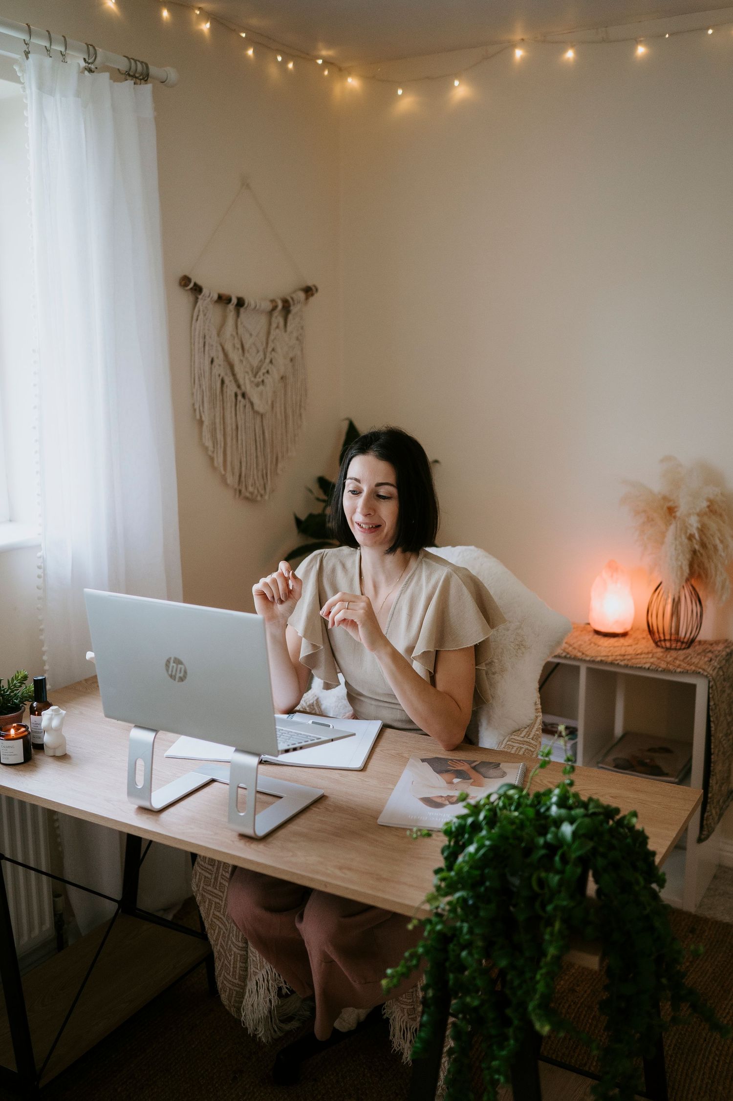 Cozy home office setup with string lights, white curtains, and potted plants creating a peaceful study atmosphere.