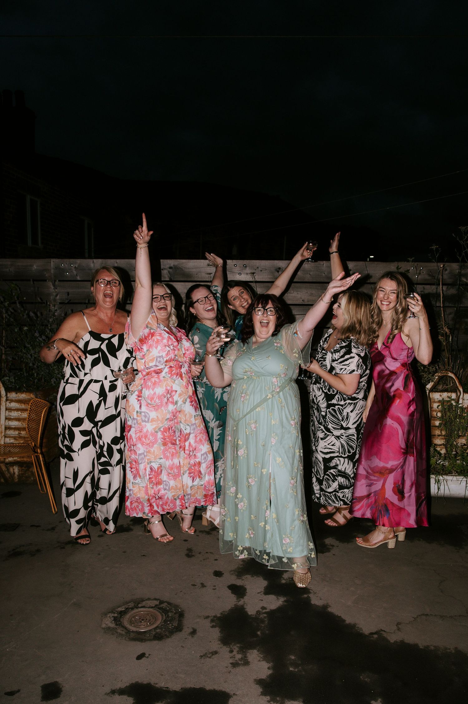 Group of people in colorful dresses dancing and celebrating at a nighttime outdoor party.