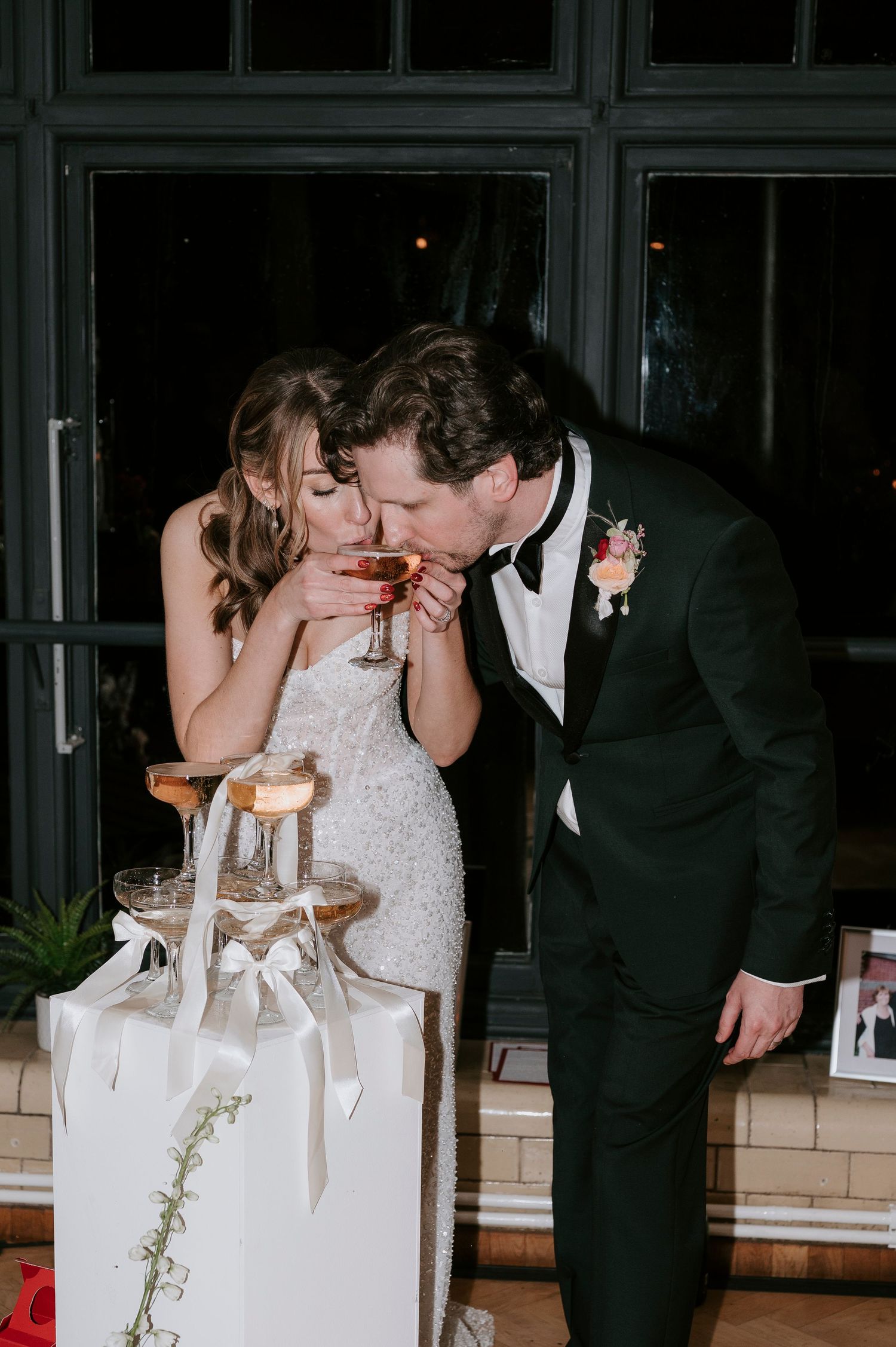 A couple in wedding attire share an intimate moment while laughing together near a decorated table.