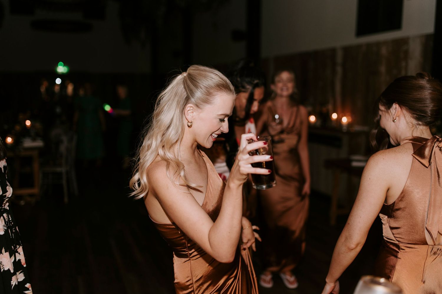 Group of people dancing and celebrating at a dimly lit nighttime party or event.