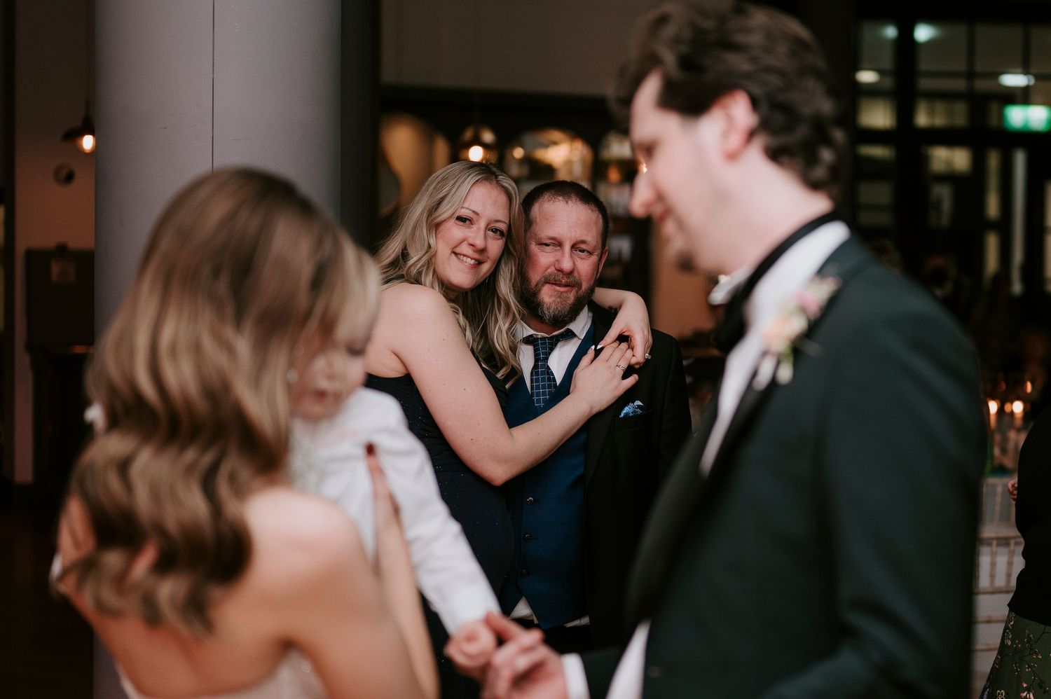 Couples dance together at an elegant evening wedding reception in a dimly lit venue.