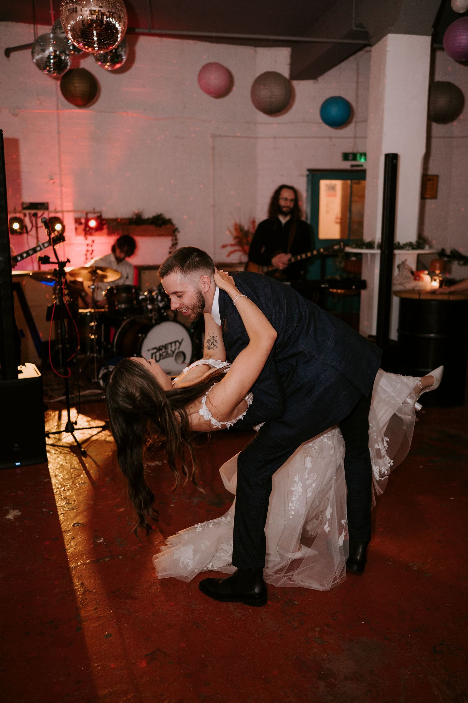 Groom dipping bride dramatically on dance floor during first dance at wedding reception.