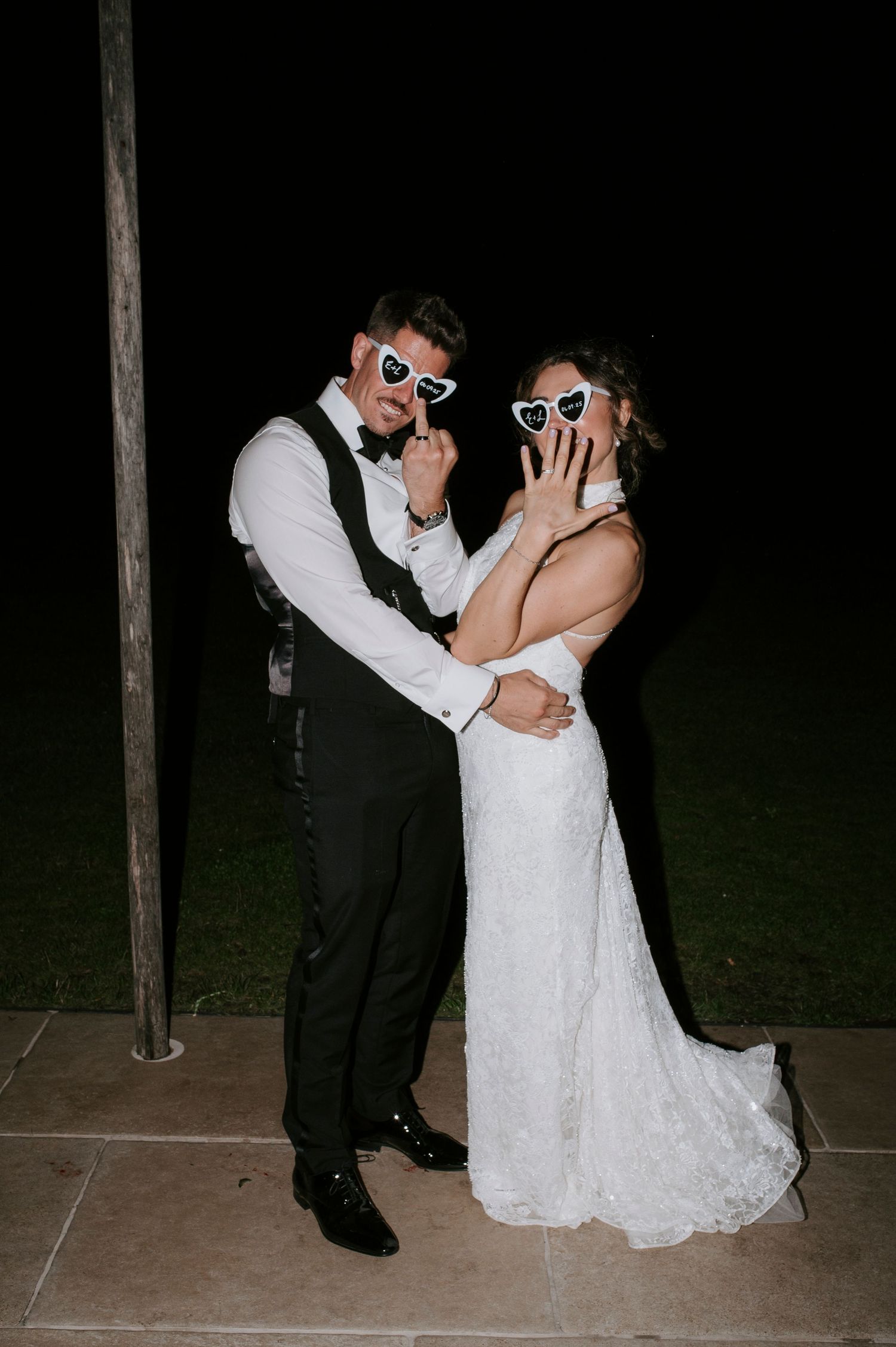 A newlywed couple wearing sunglasses share a romantic dance sequence at their wedding reception.