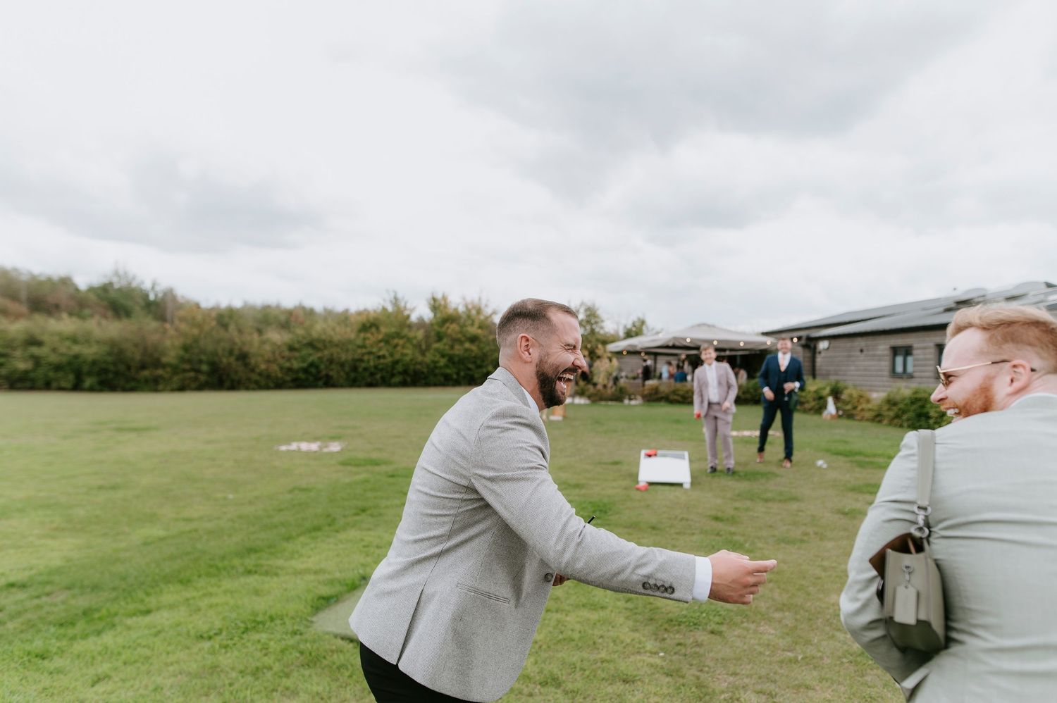 A couple embraces on a grassy field during an outdoor wedding celebration.