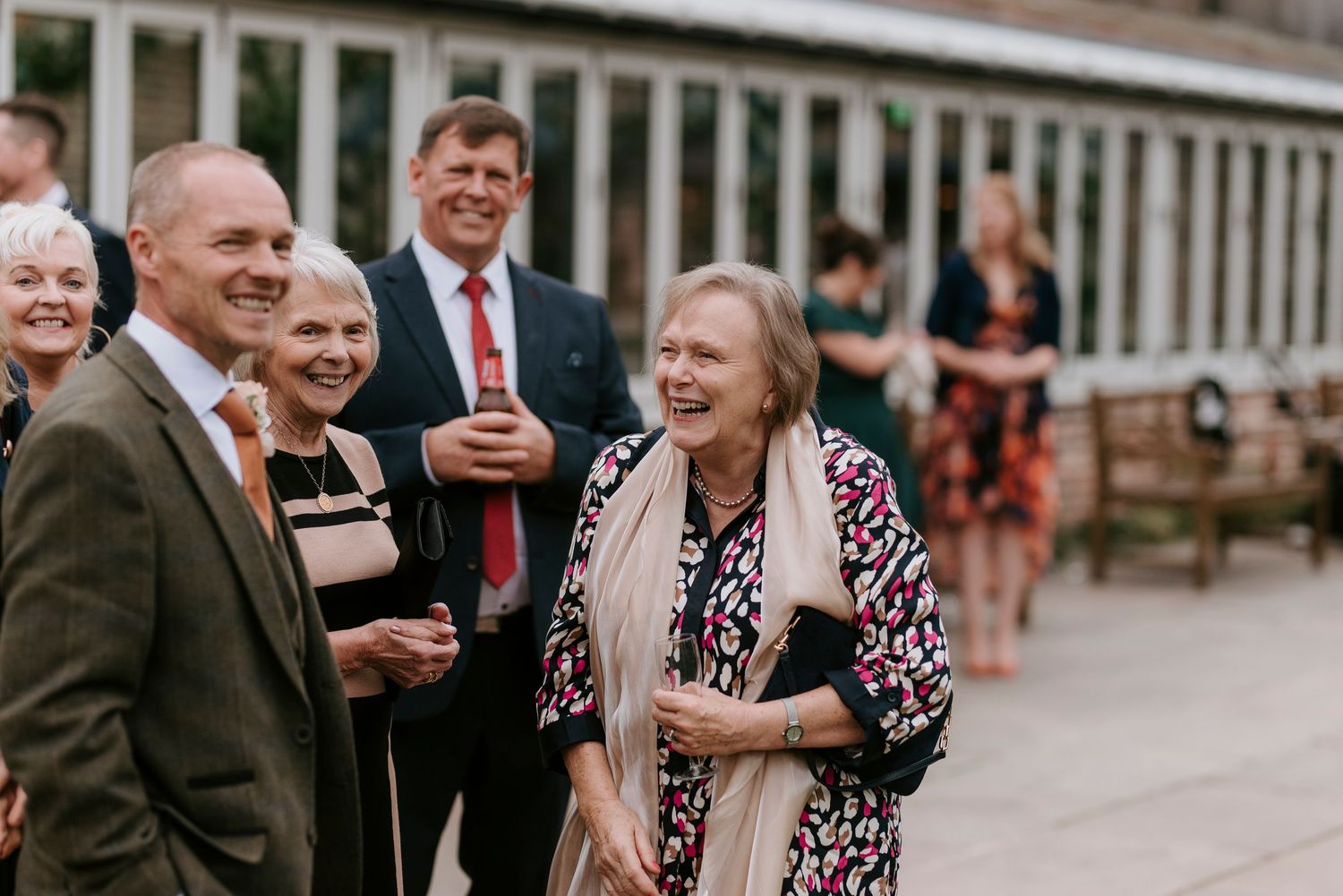 A group of guests share a laugh while enjoying drinks at an outdoor event.