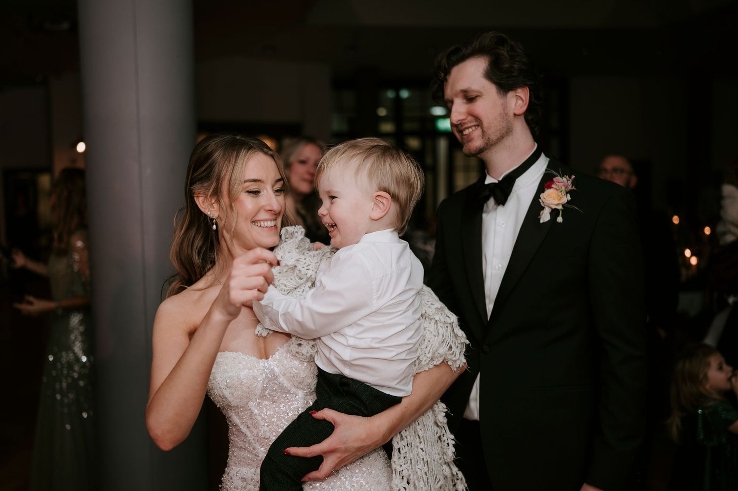 Wedding celebration at night with guests dancing and enjoying festivities in an indoor venue.