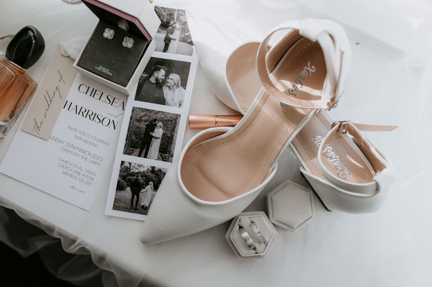 Elegant wedding details including blush pink shoes, invitations, and delicate accessories arranged in a flat lay composition.