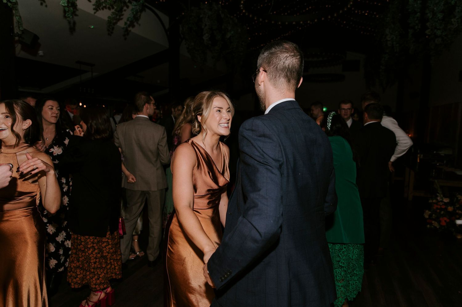 A couple dances together at an elegant evening event while other guests mingle in the background.