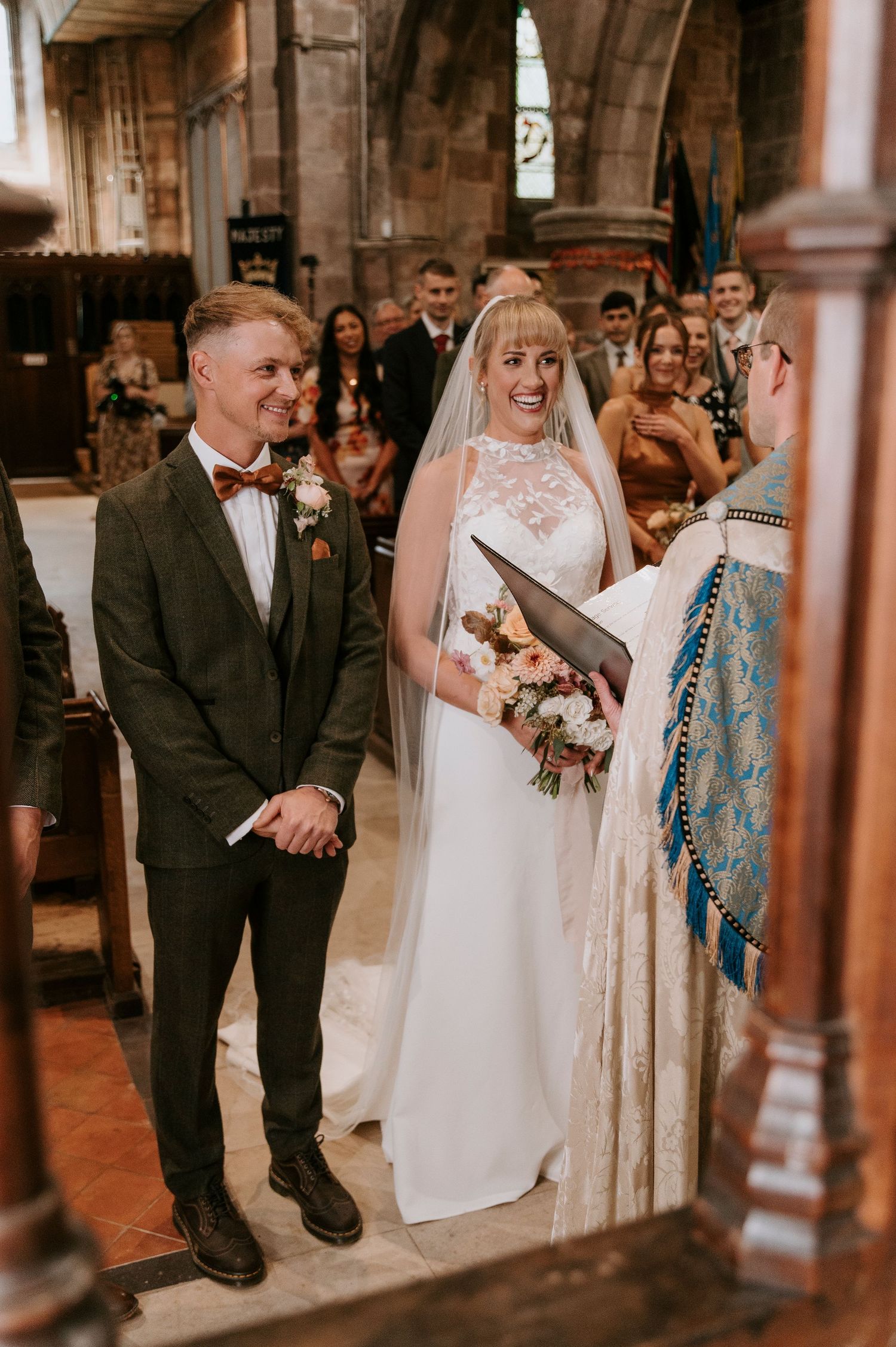 Wedding ceremony guests share joyful reactions during an emotional moment in a church interior.