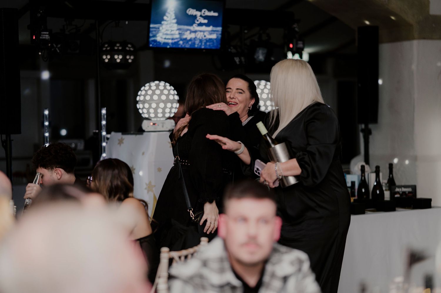 A dark nightclub scene with people dancing and socializing under disco lights and party decorations.