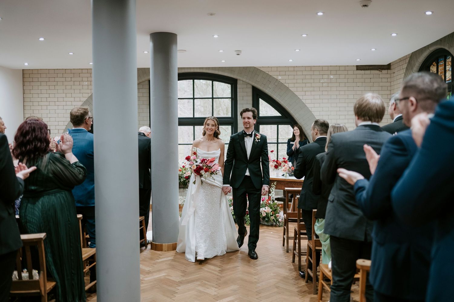 Wedding reception space with white columns and brick walls filled with seated guests.