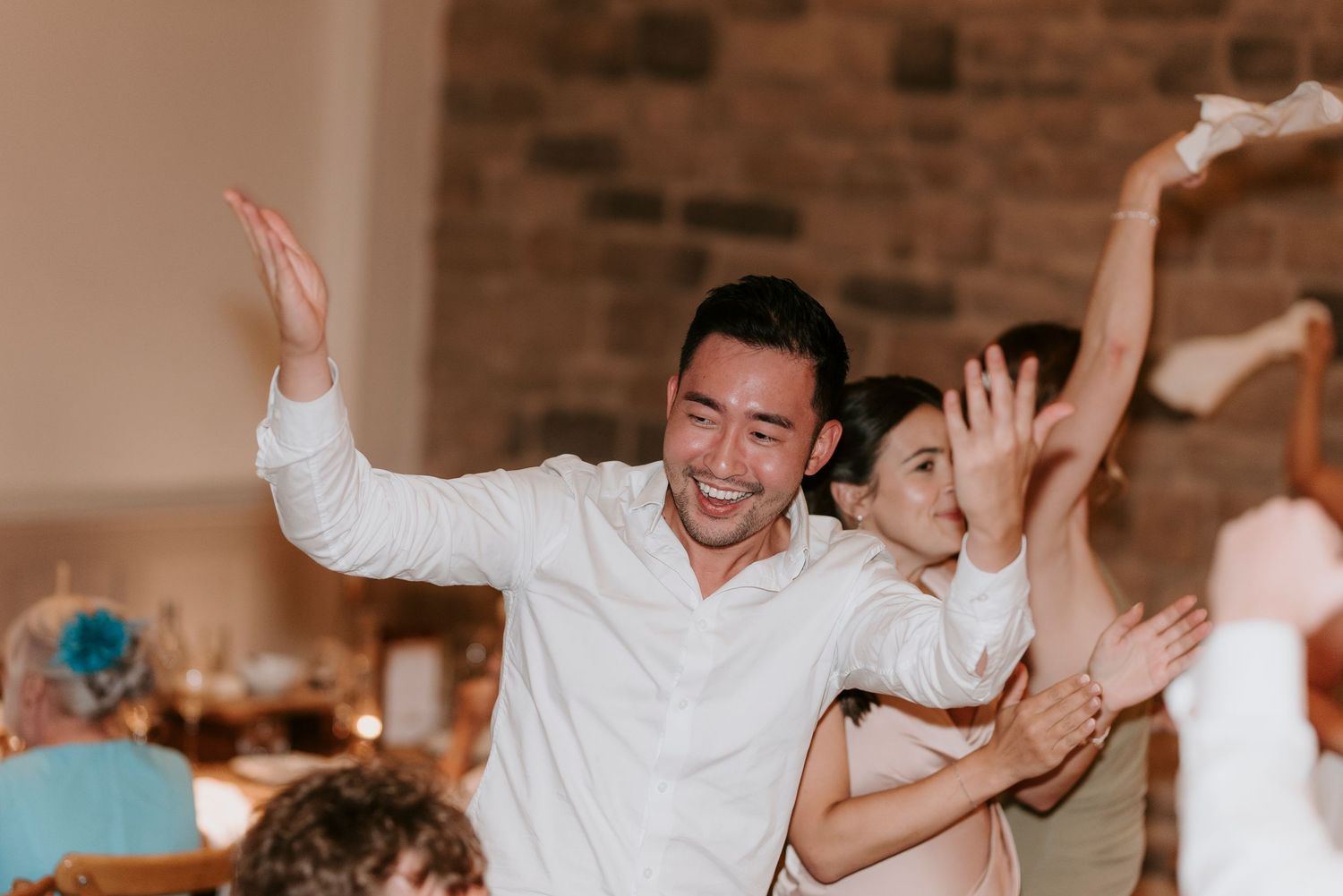 A group of wedding guests dancing joyfully on the dance floor during a reception celebration.