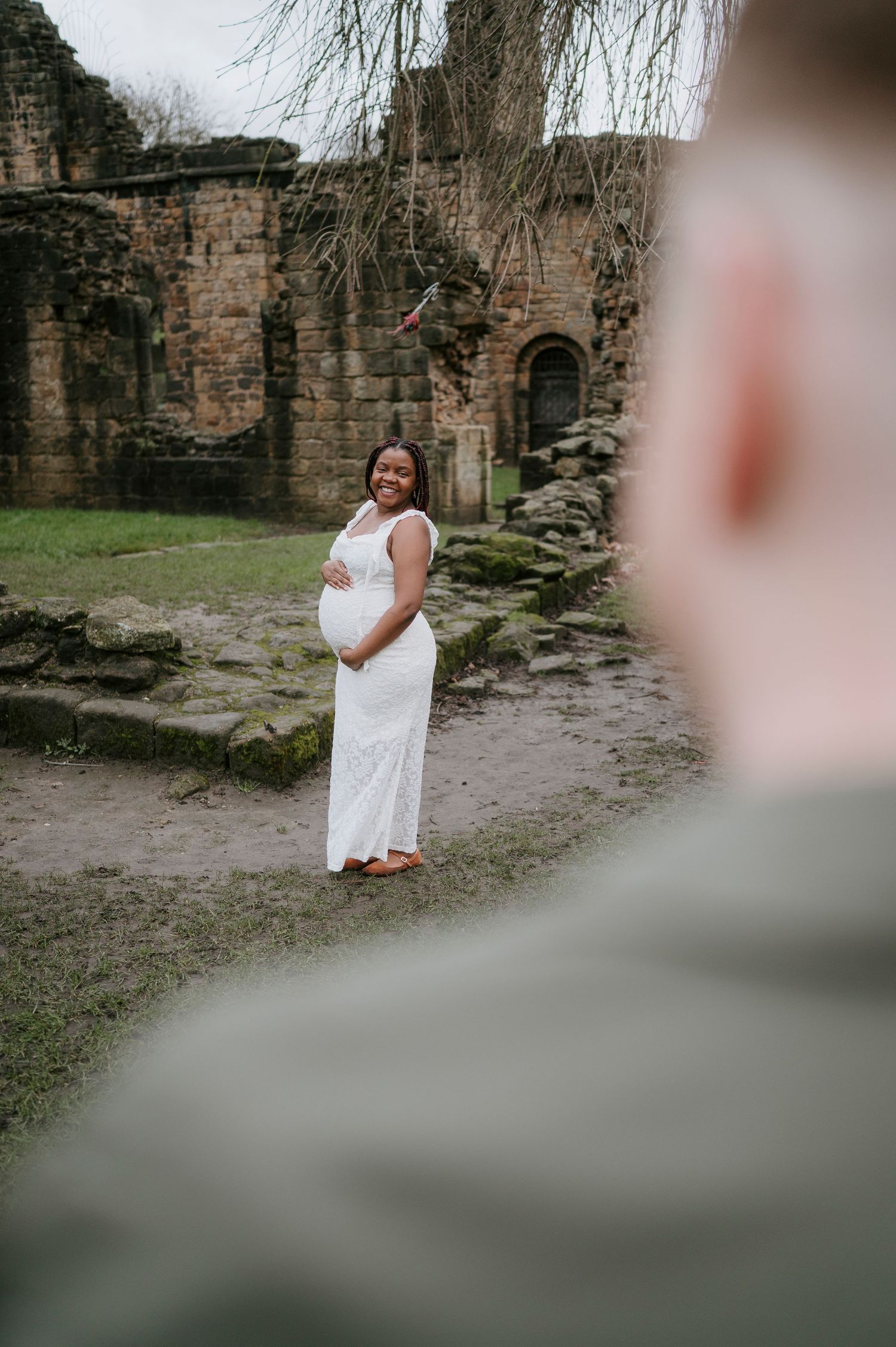 A person in a flowing white dress poses at ancient stone ruins during an outdoor photo session.