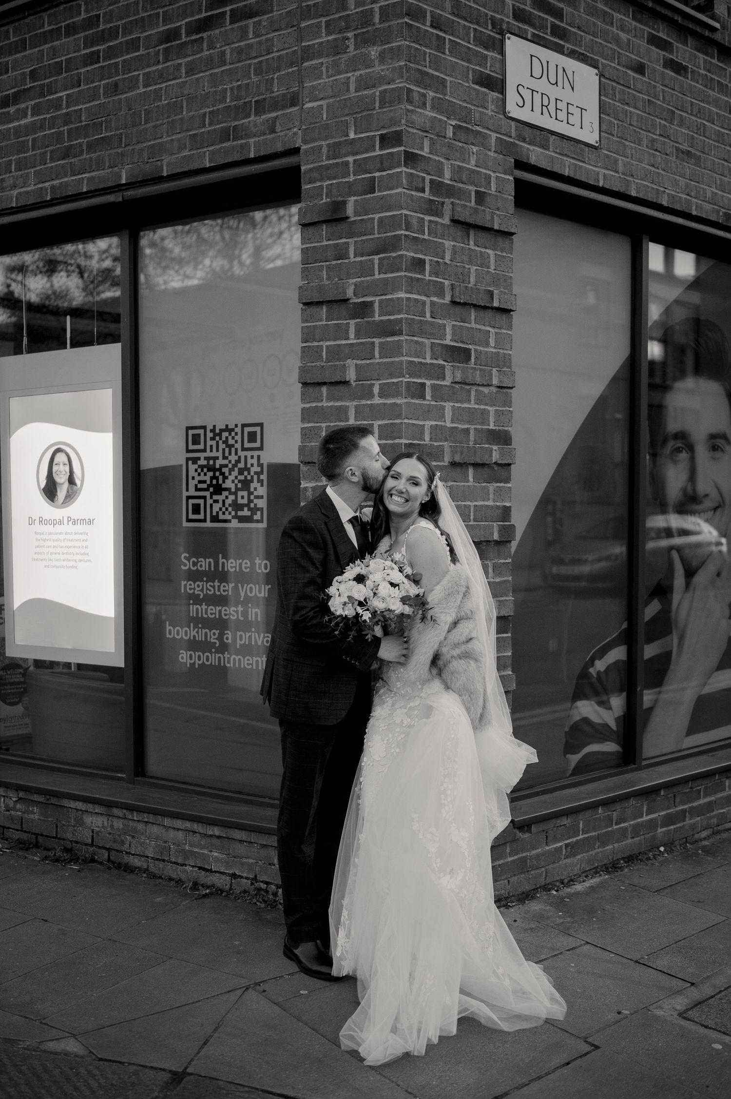 Black and white portrait of bride and groom sharing a kiss on Dun Street corner on wedding day.