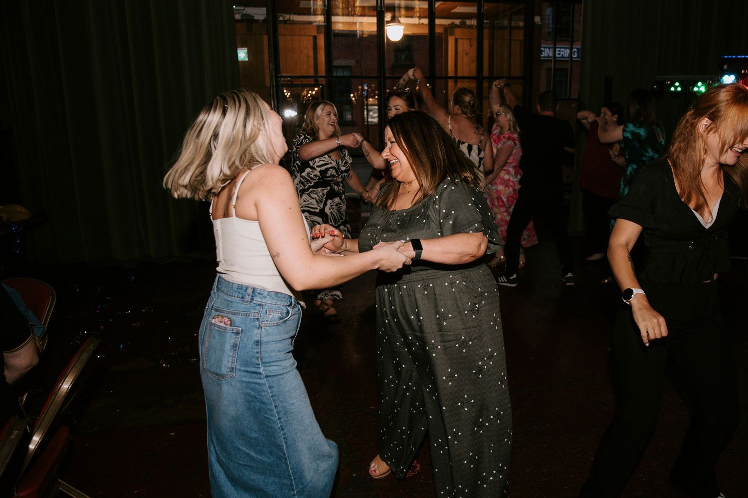 People dancing and socializing at a dimly lit nightclub or party venue.