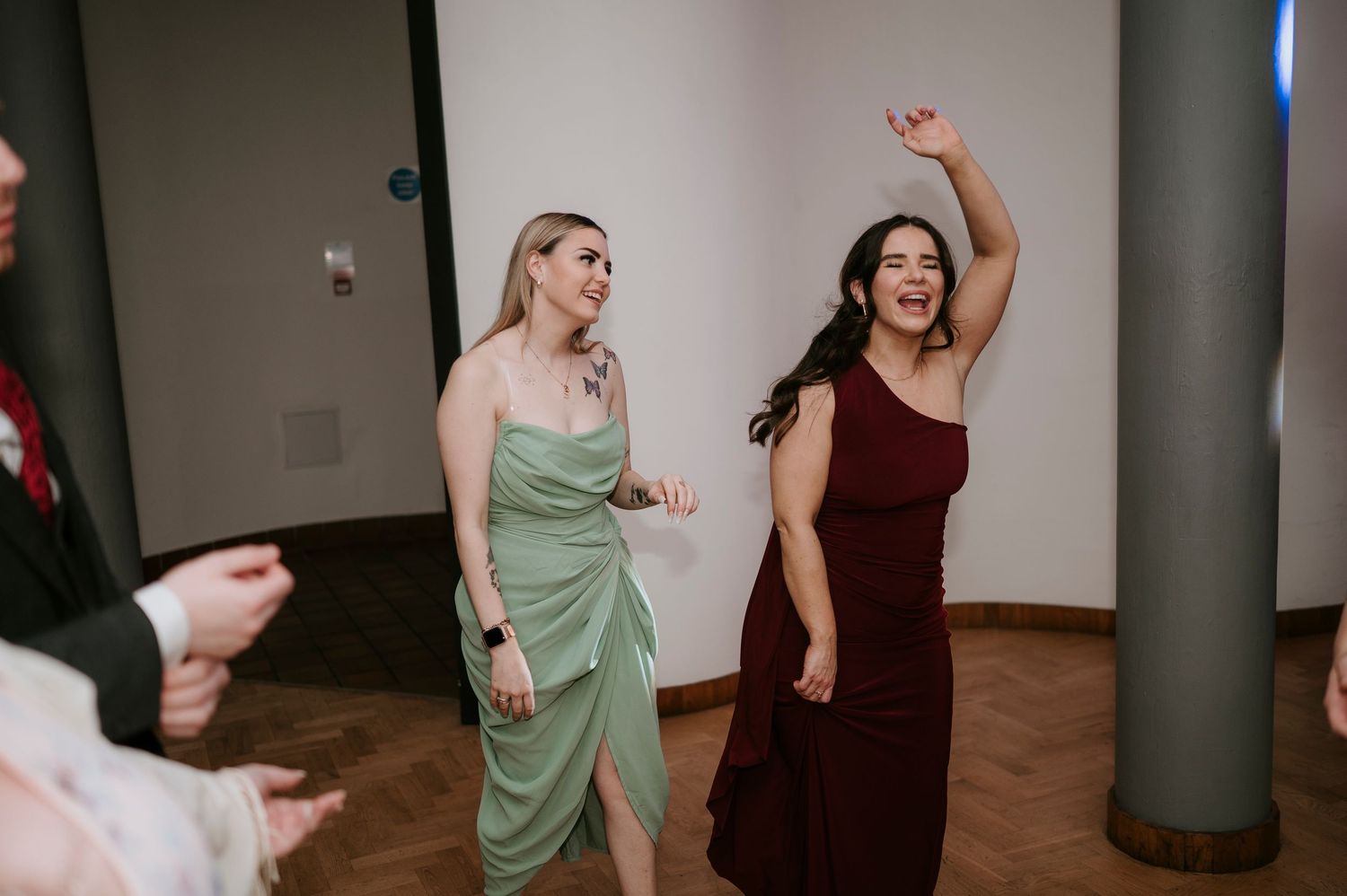 Reception guests dance and celebrate in a modern venue with columns.