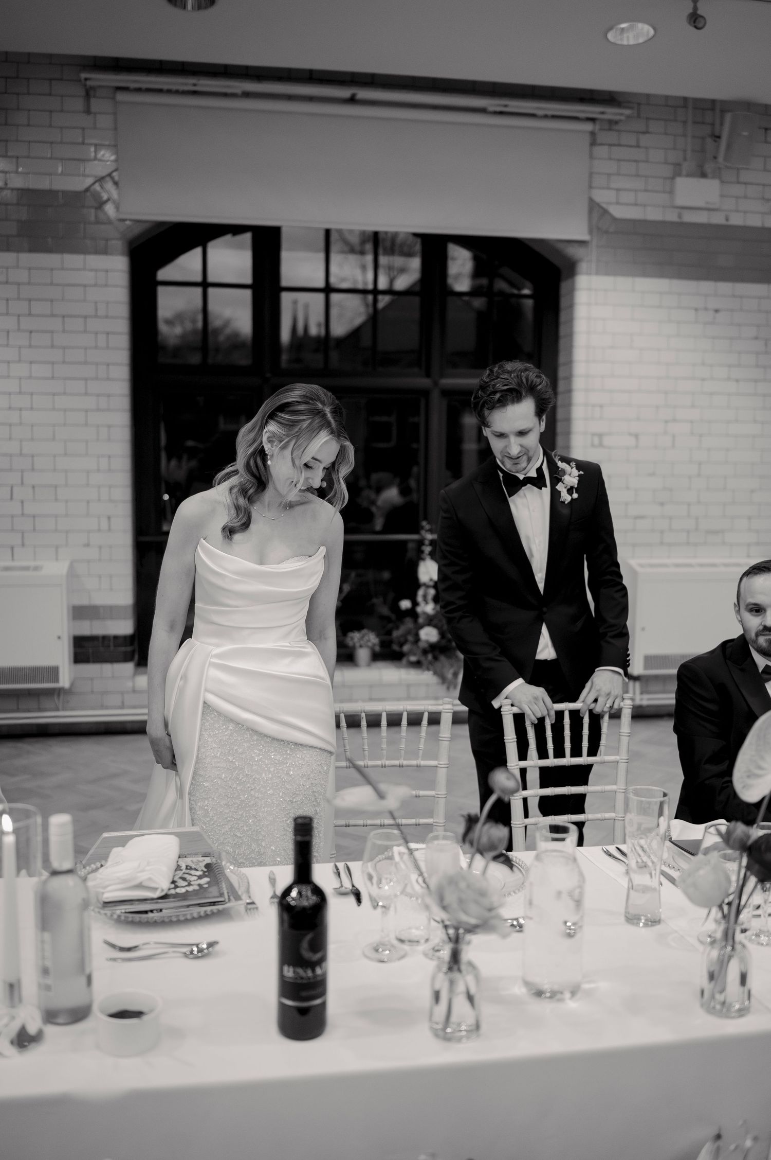 Wedding guests seated at an elegant dining table with wine glasses and place settings.