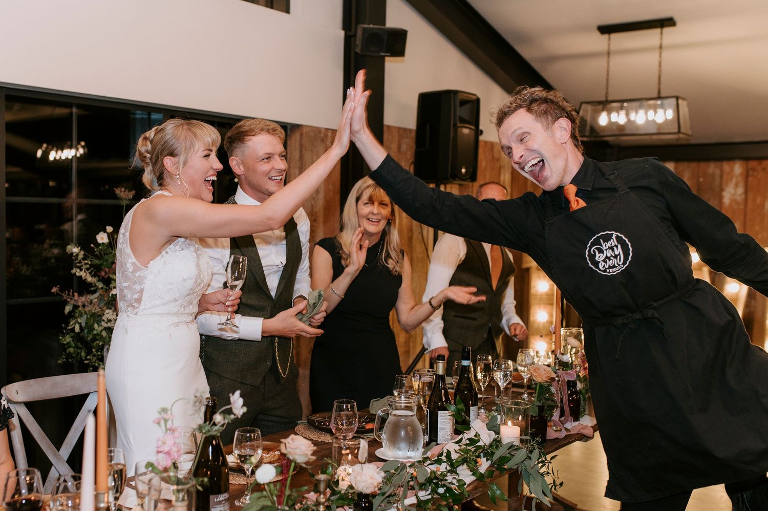 Joyful wedding reception scene with couples dancing and celebrating on a dimly lit dance floor.
