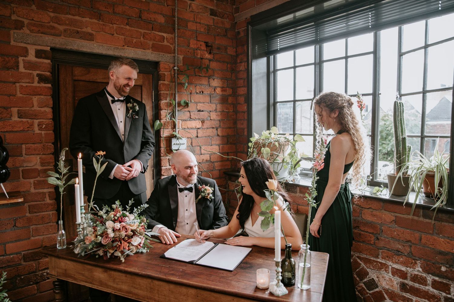 Wedding ceremony in a rustic brick-walled venue with large windows letting in natural light.