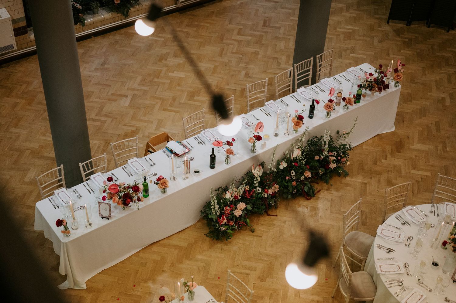 Long banquet tables with white linens and floral centerpieces arranged for a wedding reception.