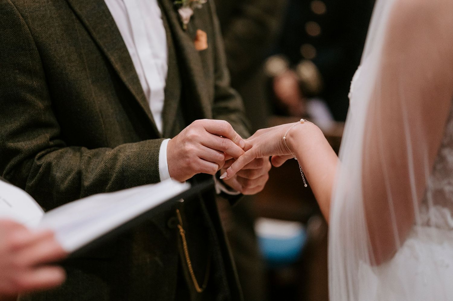 Close-up shot of hands exchanging wedding rings during an intimate ceremony.