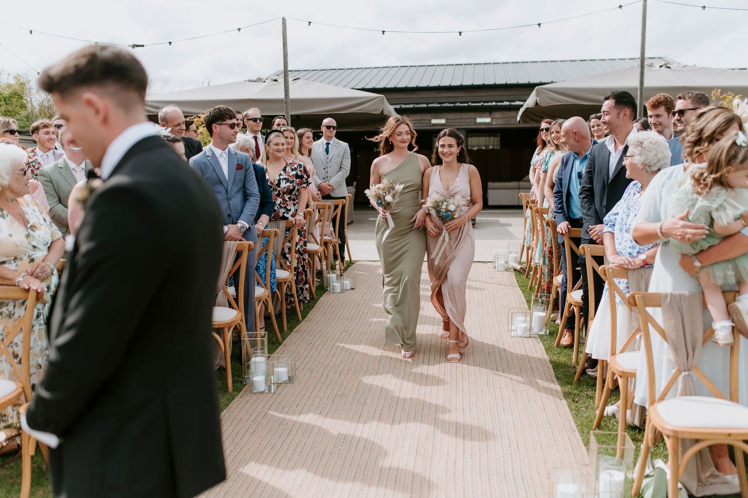 Wedding guests watch as couple shares their first dance in an outdoor reception venue with string lights overhead.