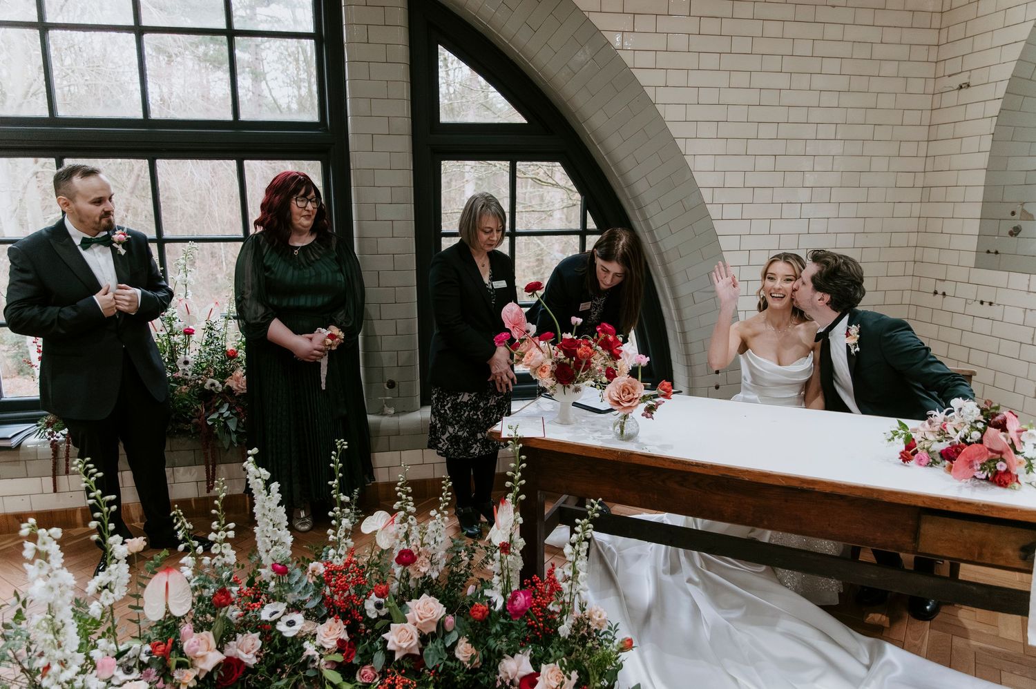 Wedding ceremony setup with white brick walls and wooden benches arranged in rows for guests.